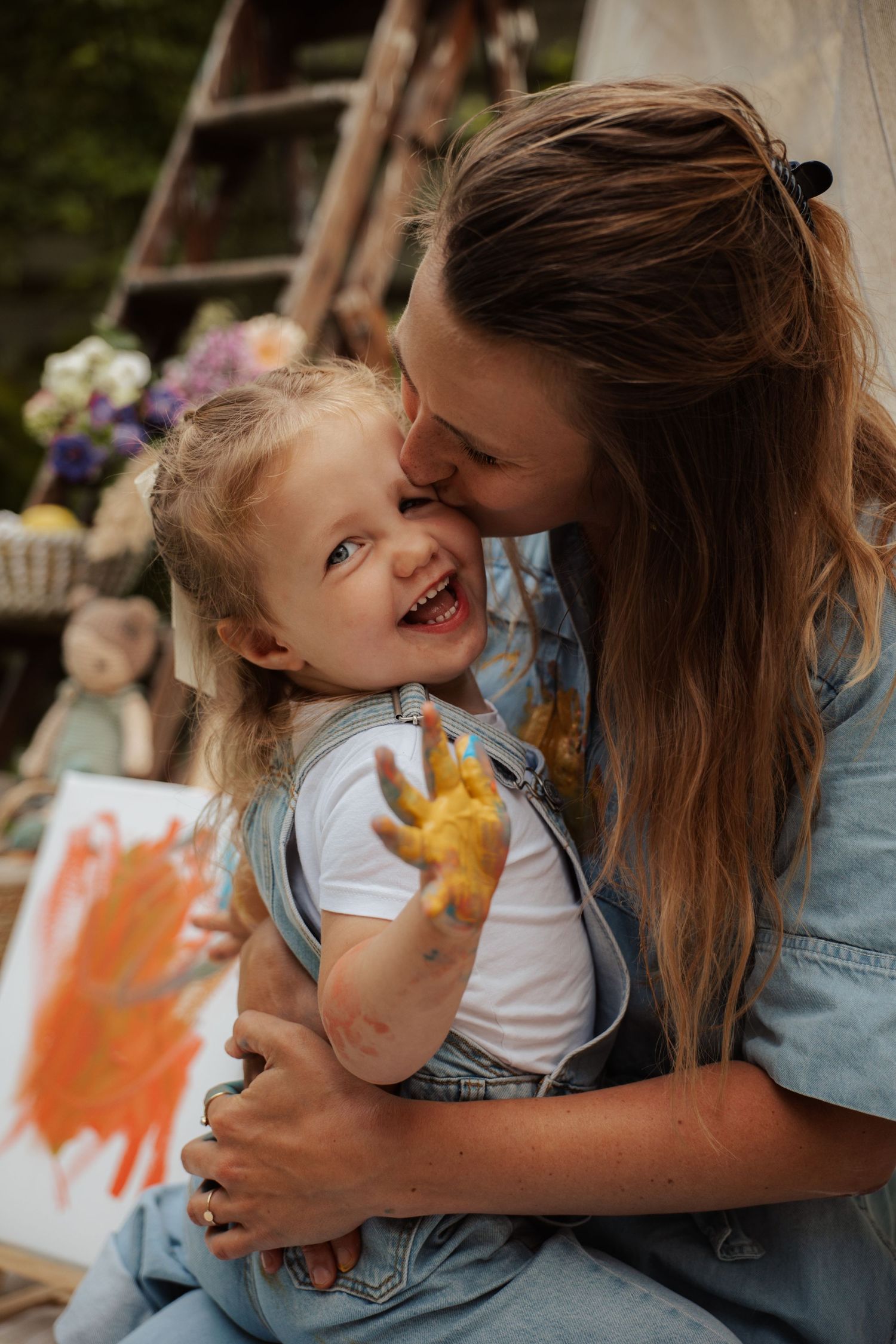 A tender moment of laughter and creativity during an outdoor painting activity.