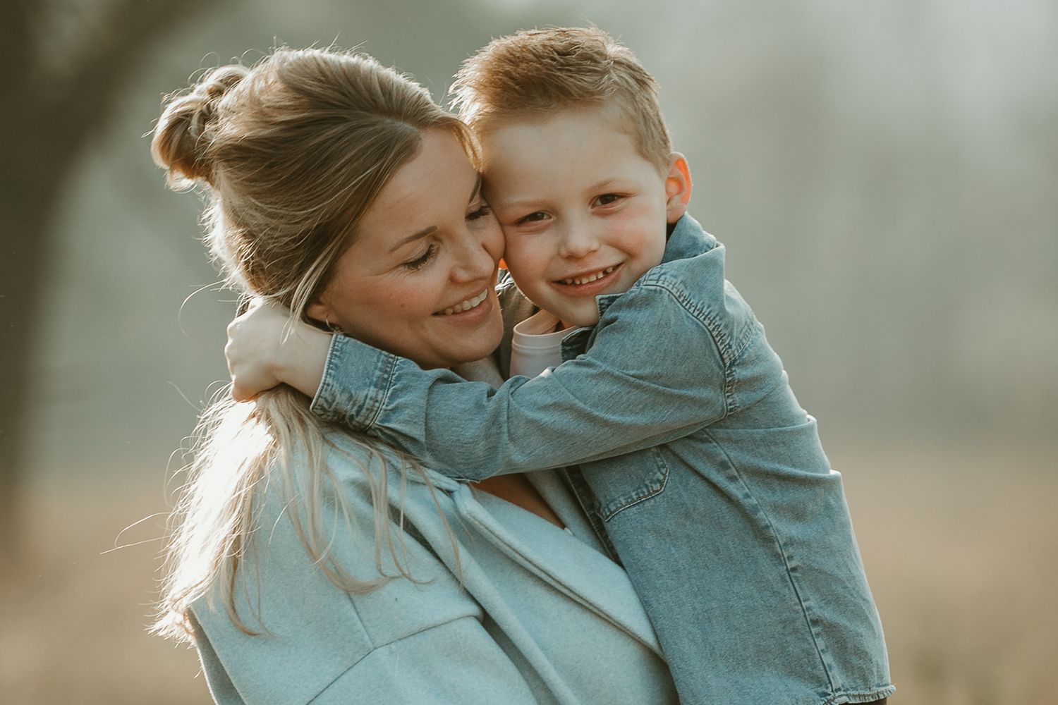 Tender embrace captured in soft lighting during outdoor family photoshoot.
