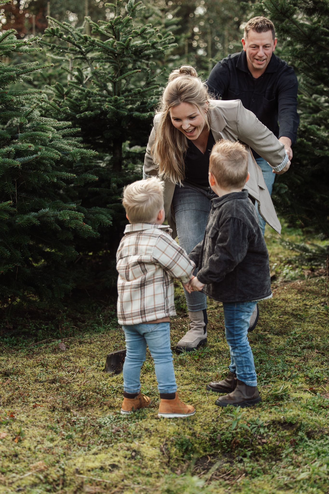 Playful family moment captured in a Christmas tree farm setting.