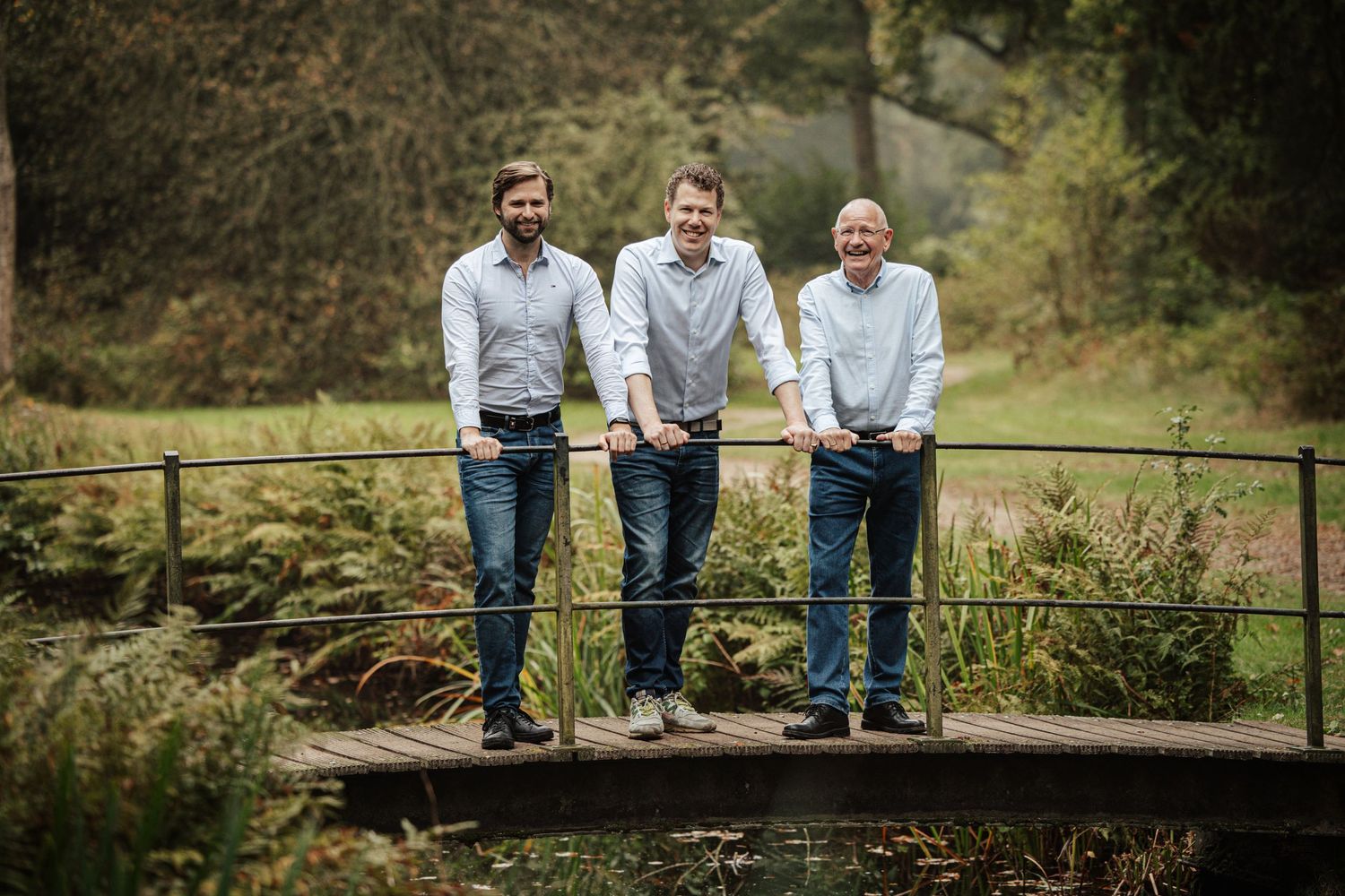 People standing together on rustic wooden bridge in nature setting.