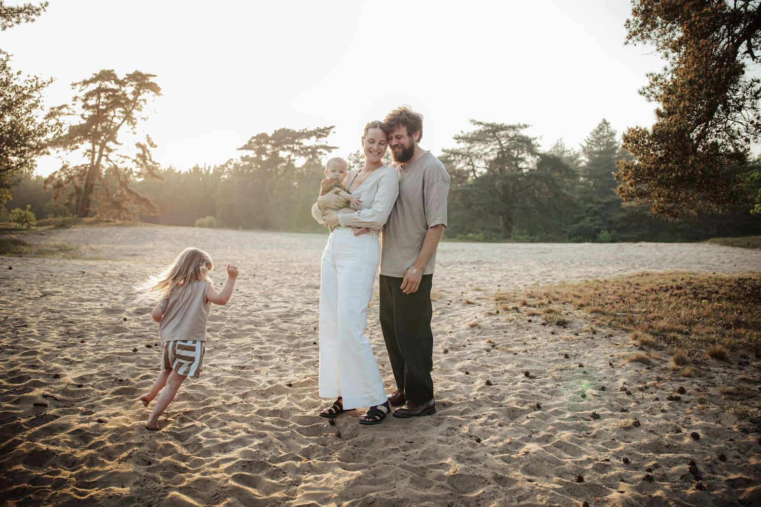 Family enjoying a playful moment together on a sandy beach at sunset.