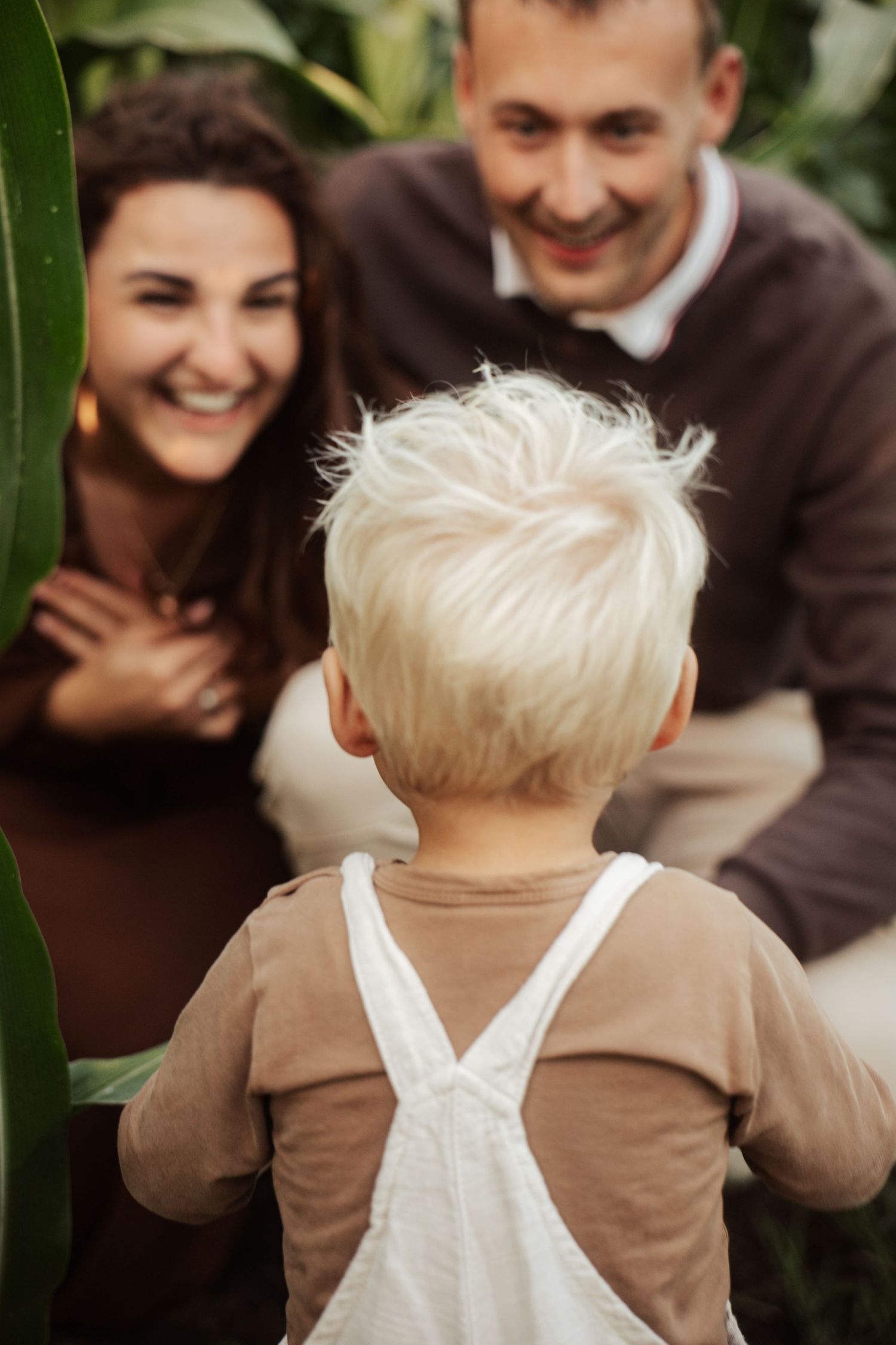 Child in brown clothing and white overalls playing outdoors.