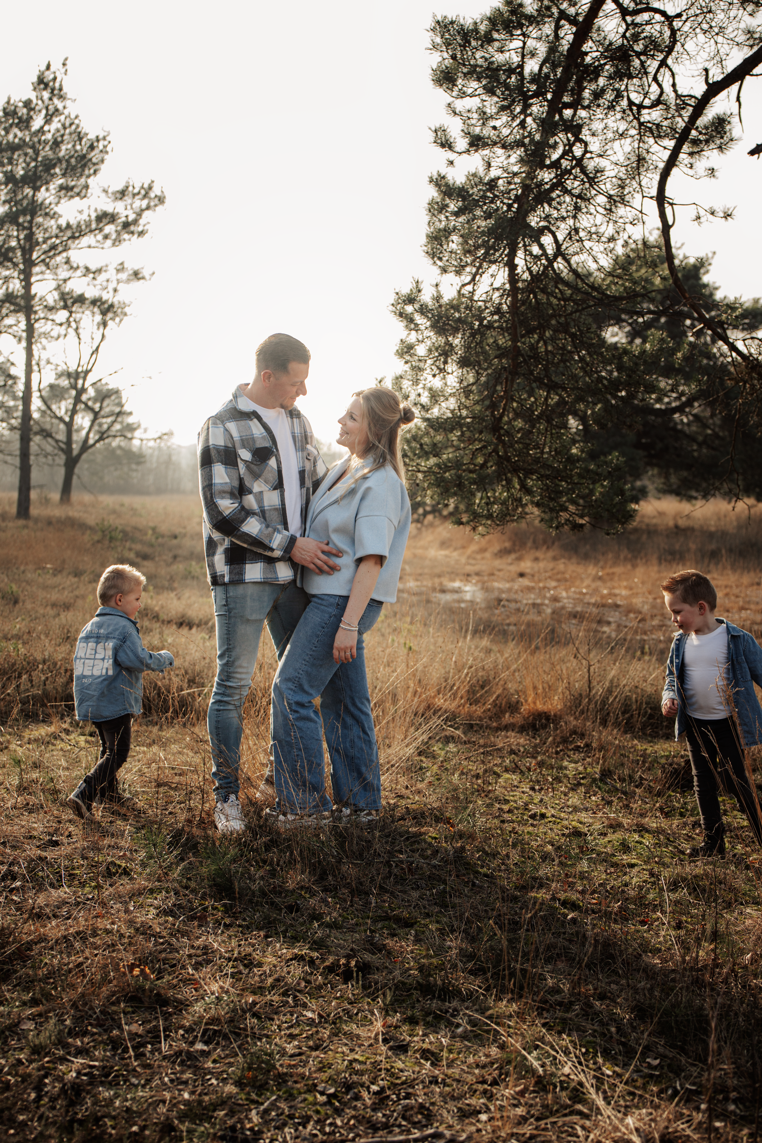 Family walking together through a sunlit field at sunset.