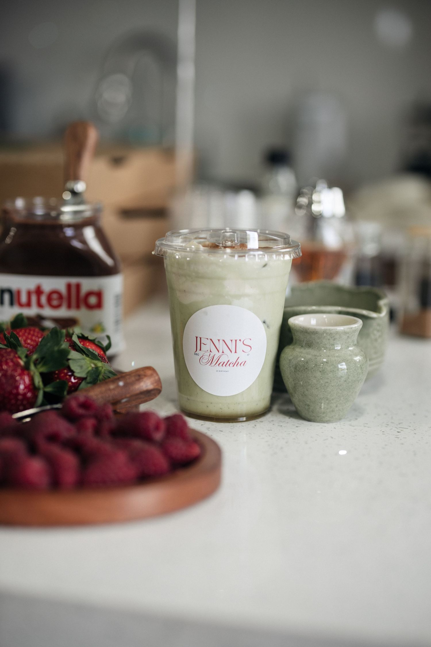 Various dessert jars and spreads including Nutella arranged on white surface with berries.