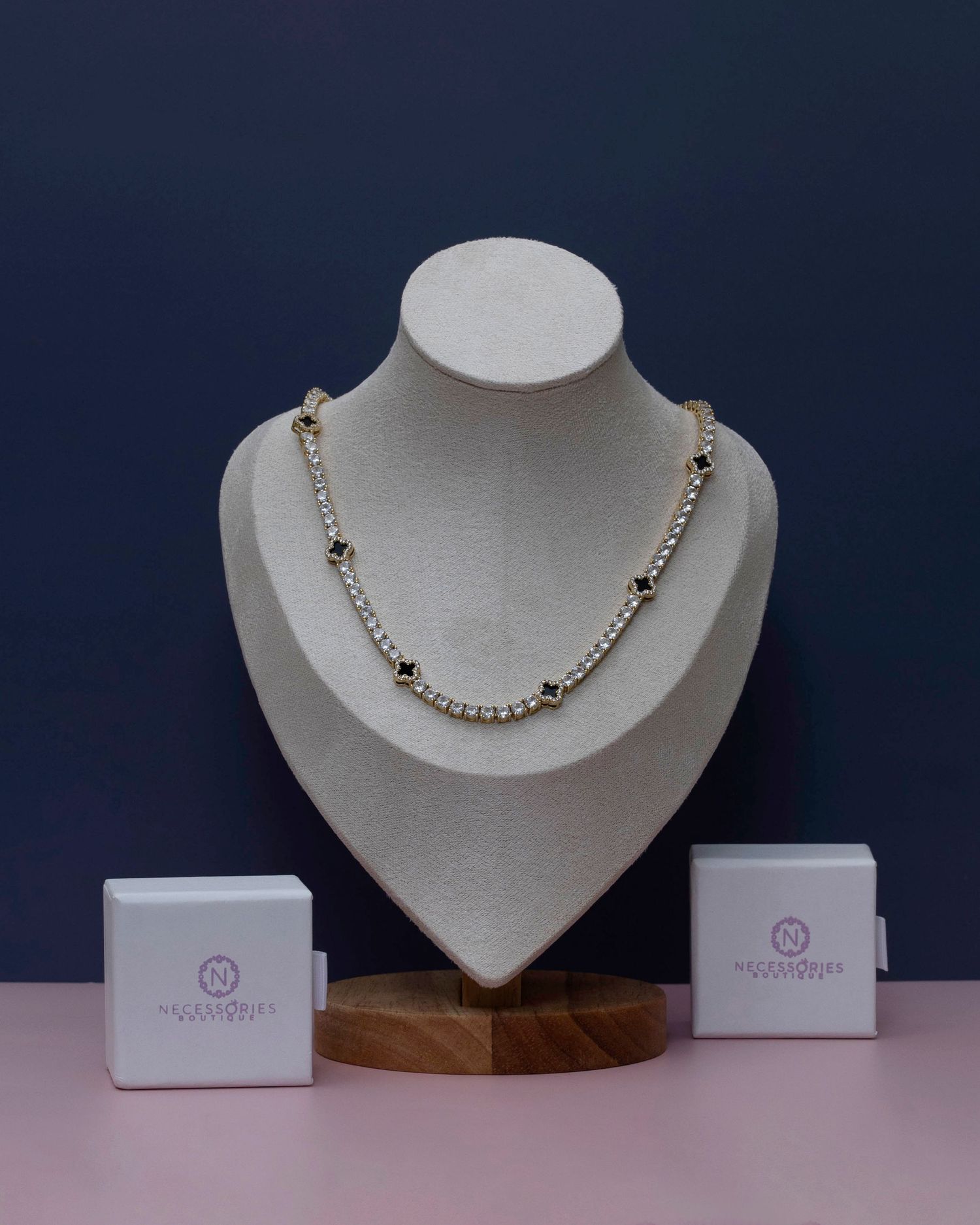 A silver and pearl necklace displayed on a white bust form against a dark blue background.