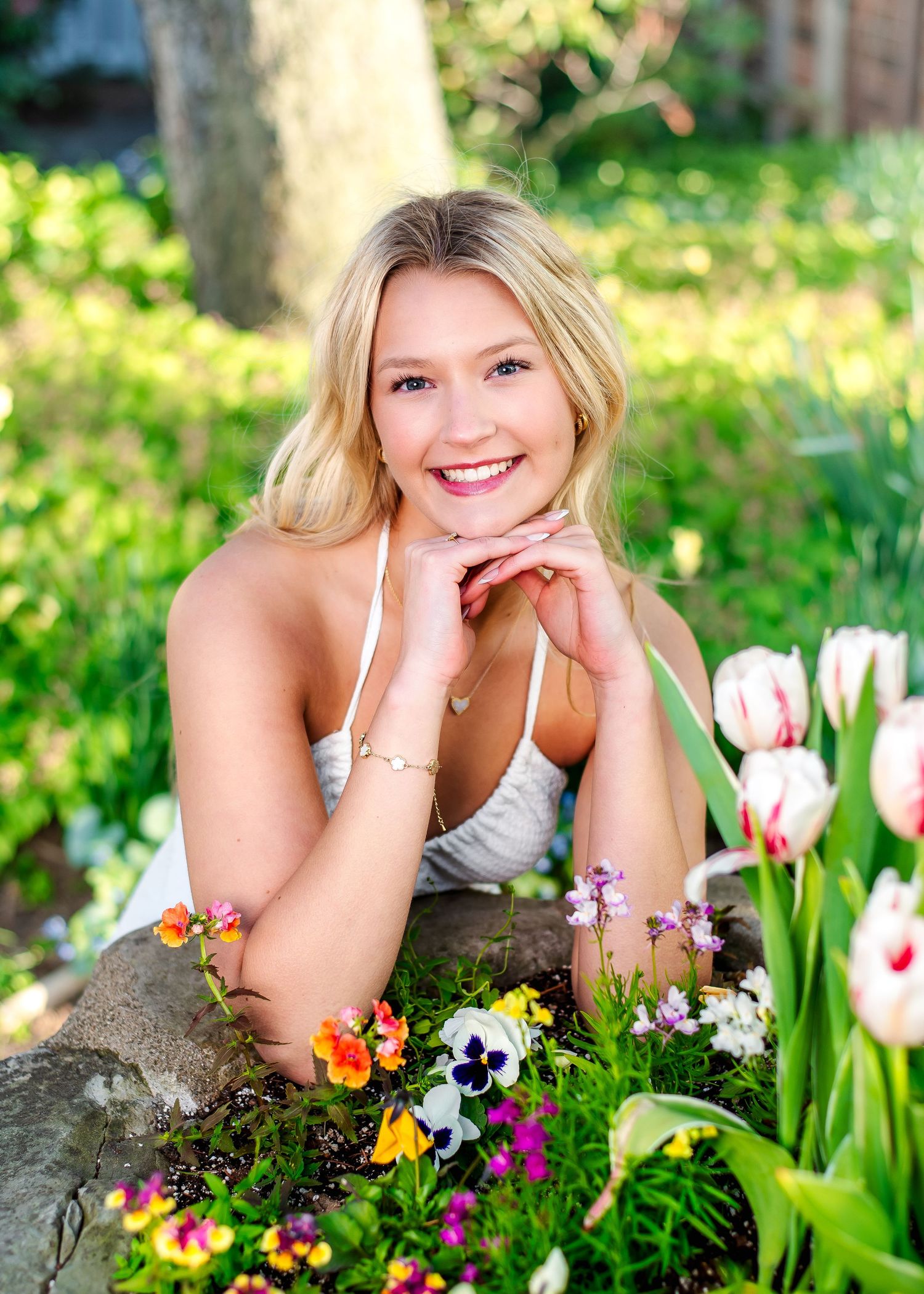 Person lying on stone wall surrounded by colorful spring flowers and tulips.