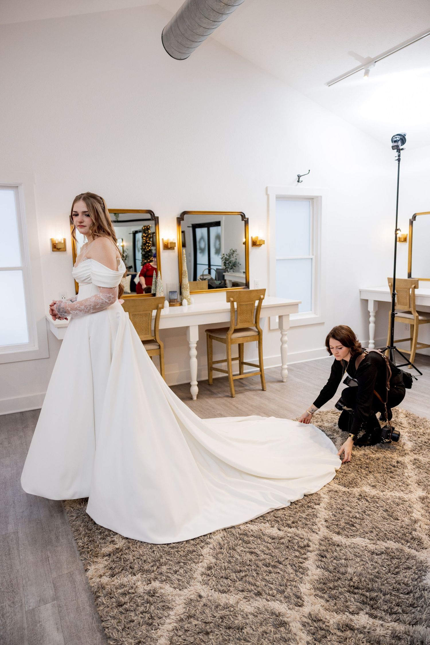 Behind-the-scenes preparation of a wedding dress being arranged on a beige carpet.