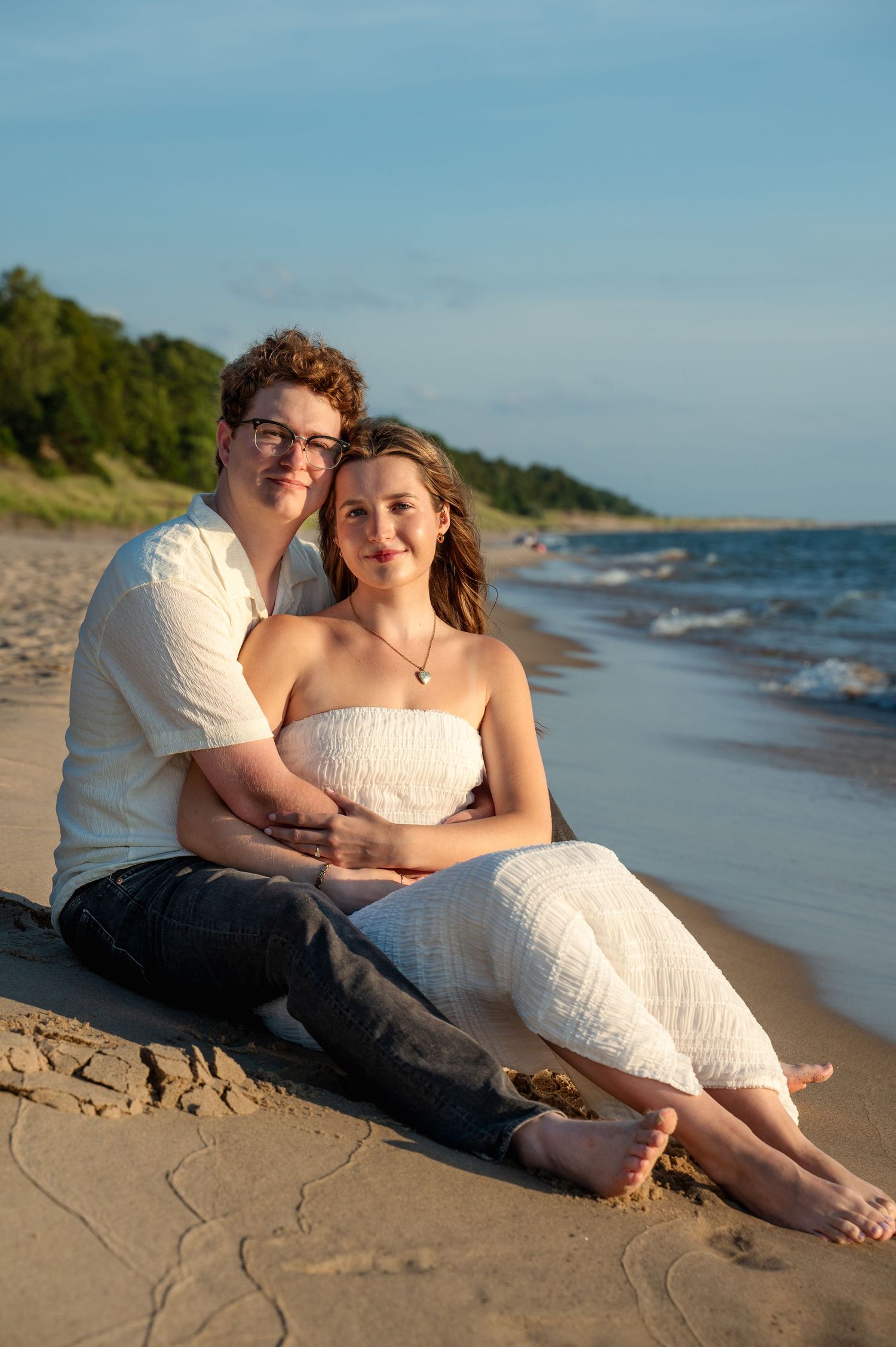 Couple relaxing together on a sandy beach during golden hour.