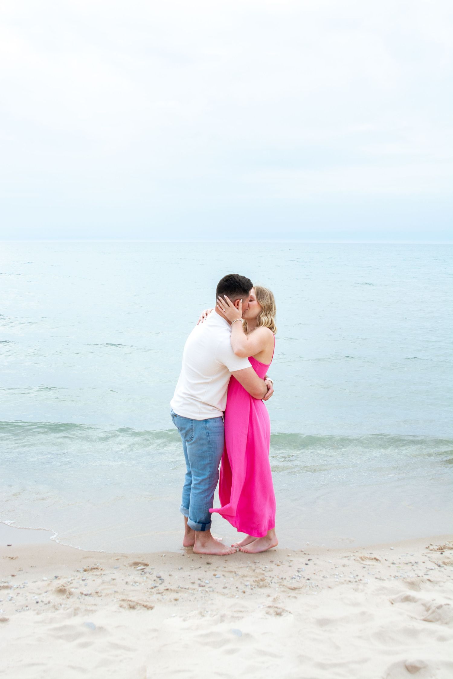 Couple sharing an intimate moment on a serene beach with soft pastel colors.