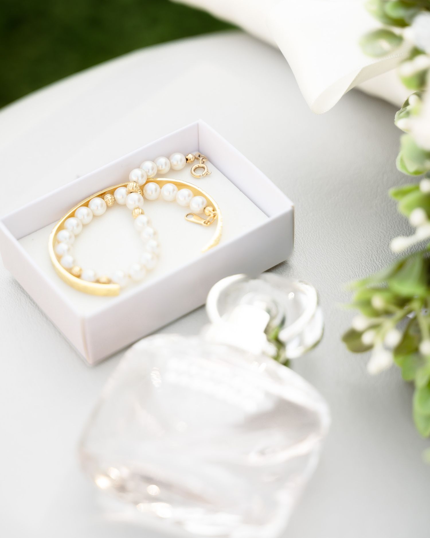 Delicate white jewelry boxes with gold accents displayed on a clean white surface with greenery.
