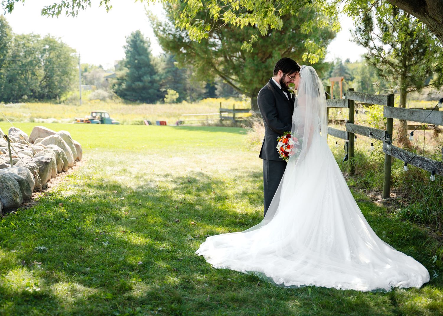 A romantic wedding portrait of a couple in a sunlit garden with a flowing white dress.
