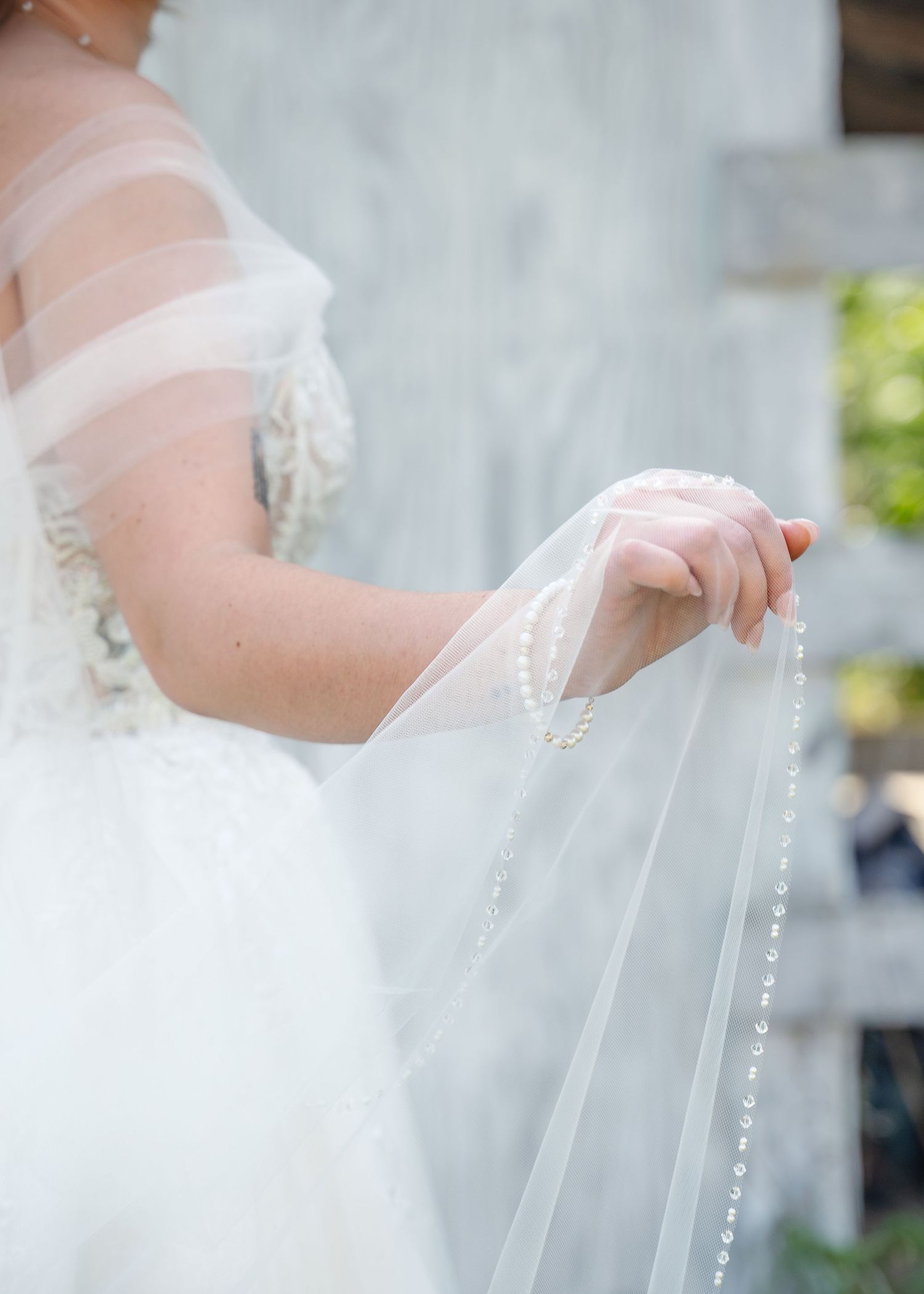 Close-up detail of a bride's delicate veil with beaded trim flowing in the breeze.