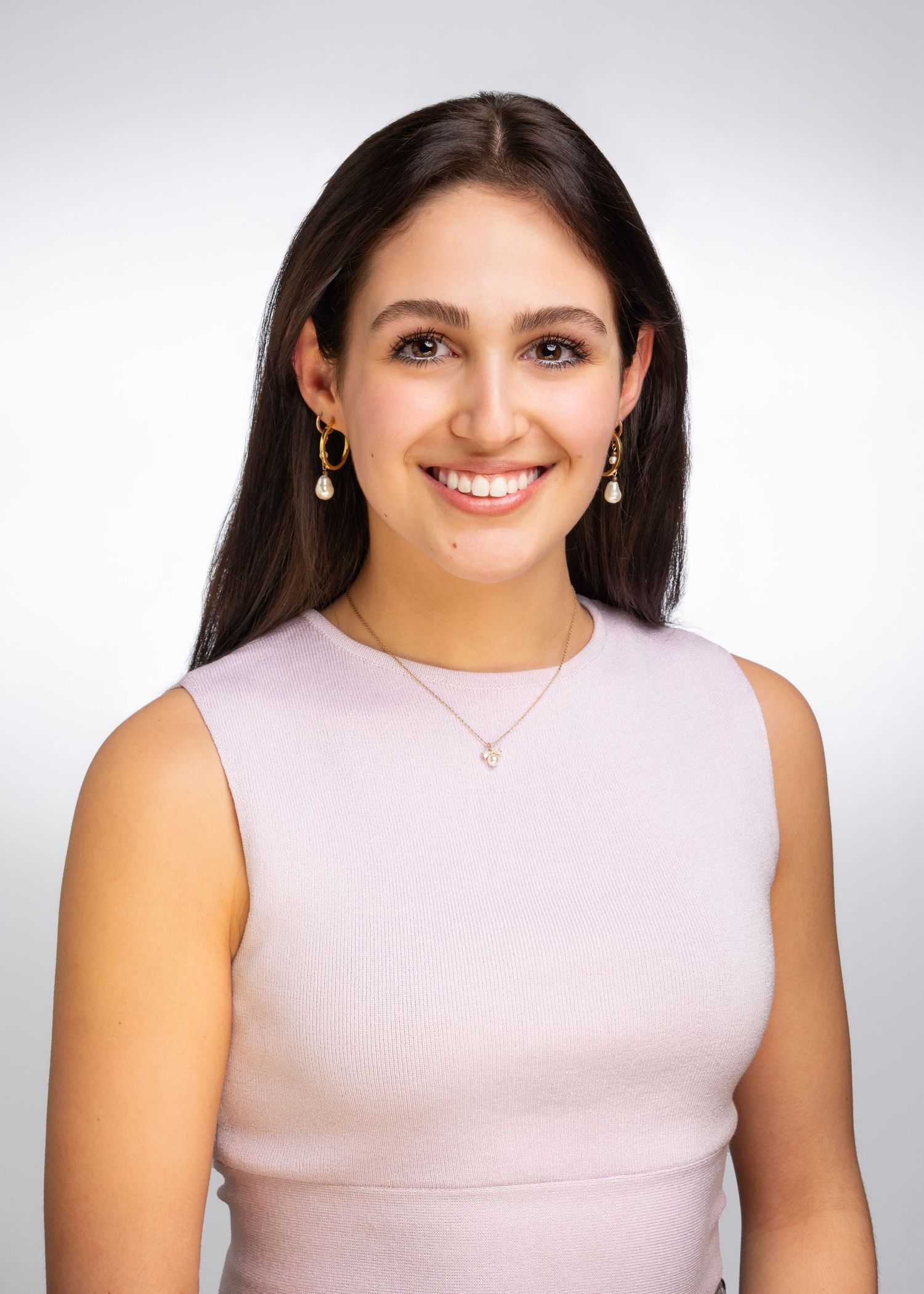 Professional headshot against white background wearing a pink sleeveless top.