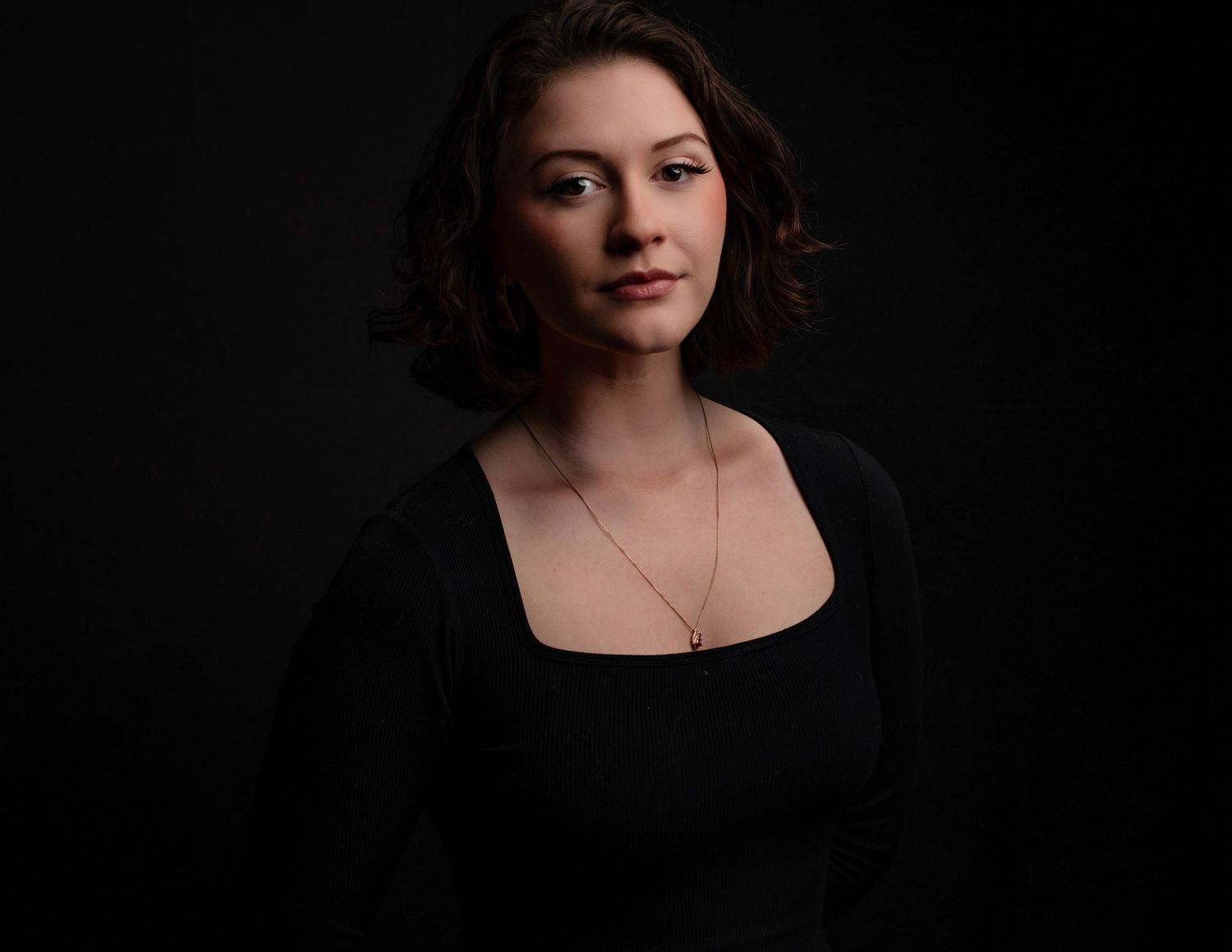 Moody studio portraits with minimalist lighting on black background.