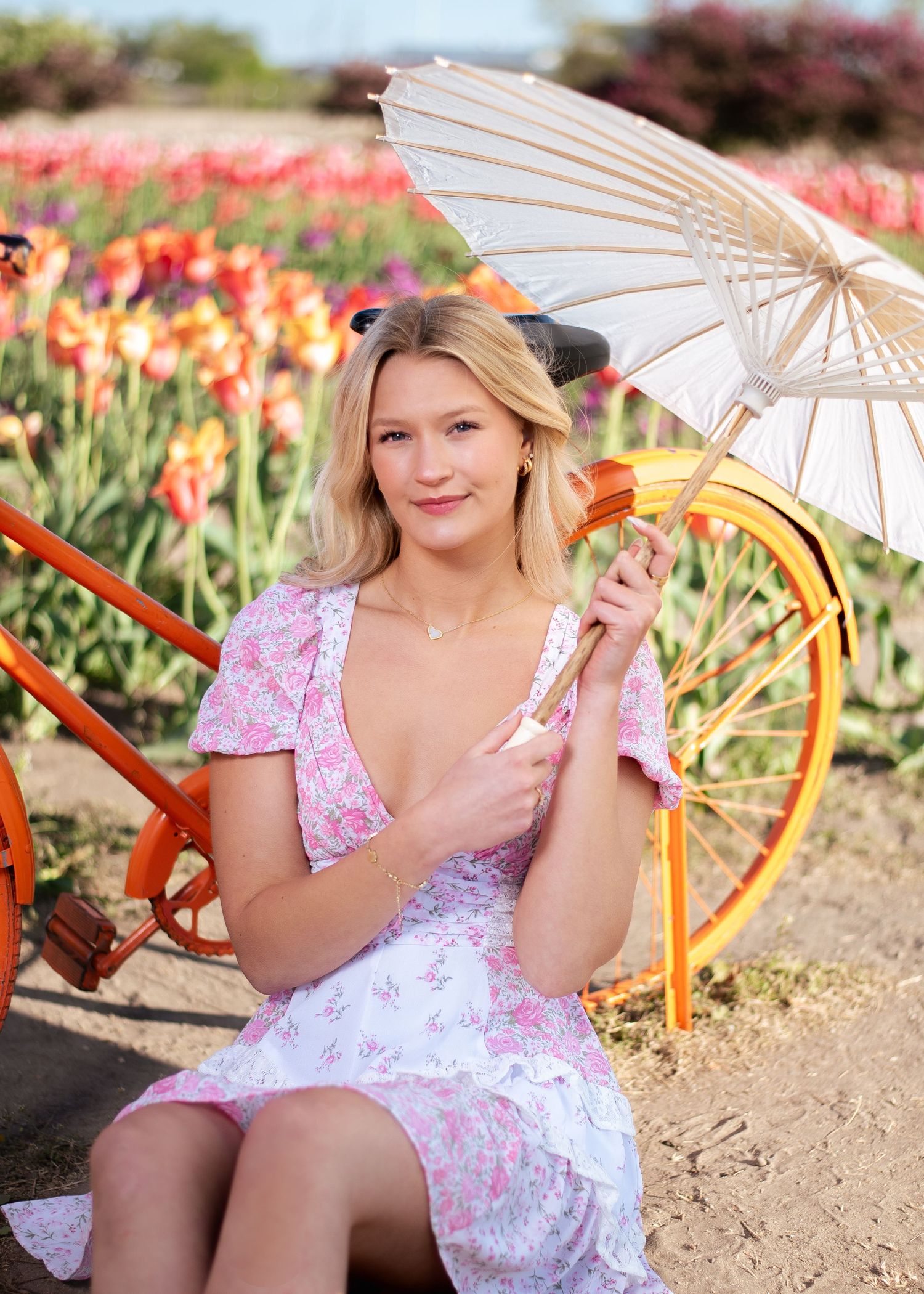 Vintage-inspired scene with parasol and orange bicycle among blooming flowers.