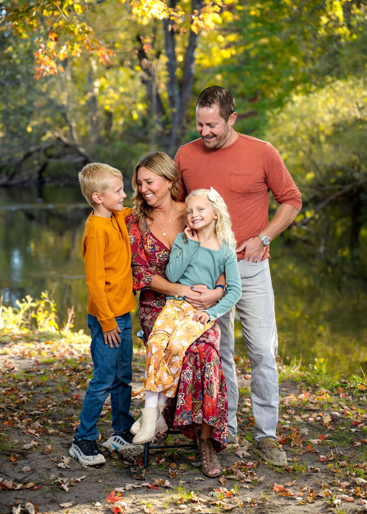 A happy family shares a candid moment together by a pond in autumn.