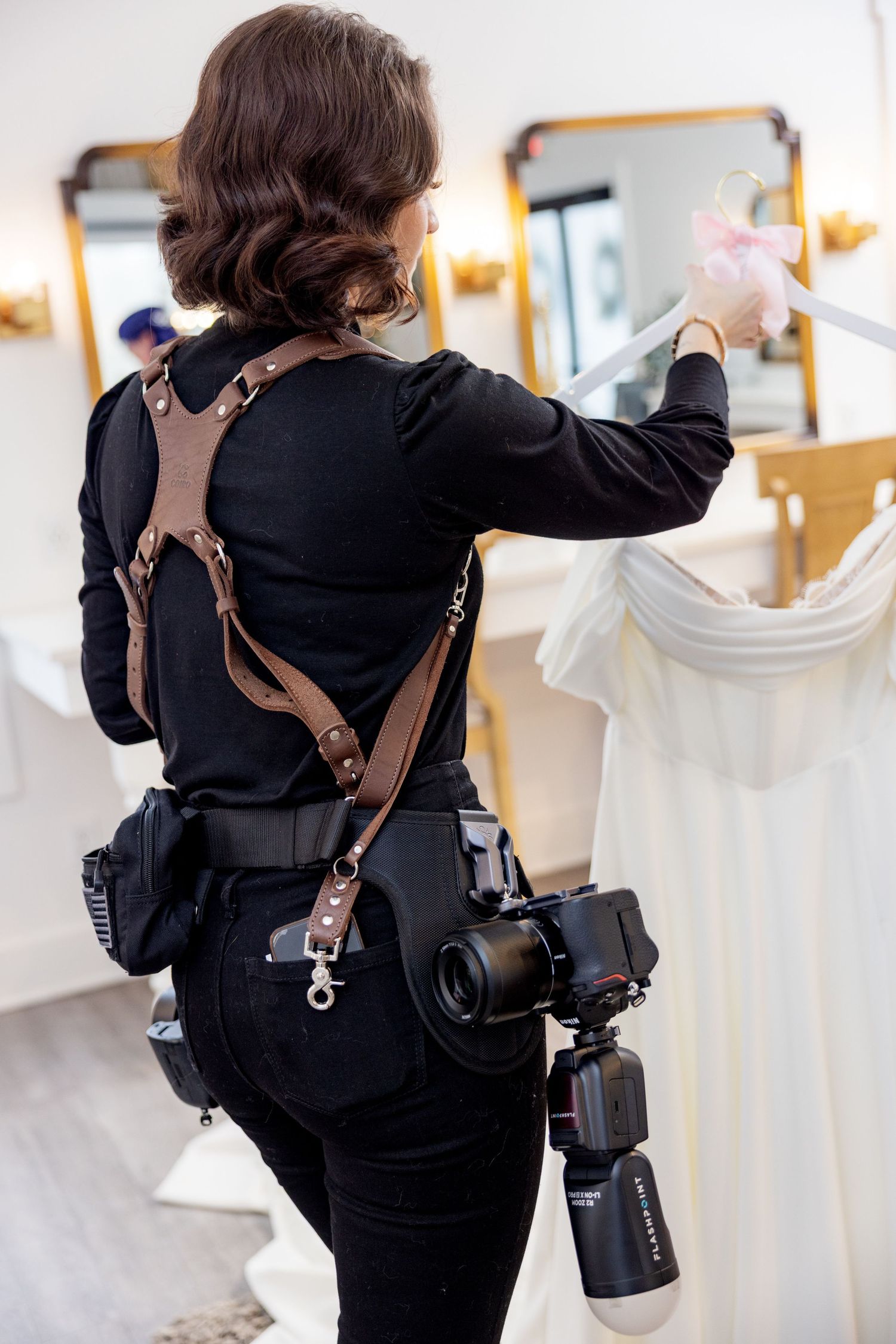 Wedding photographer wearing black with multiple cameras and gear during a photo session.