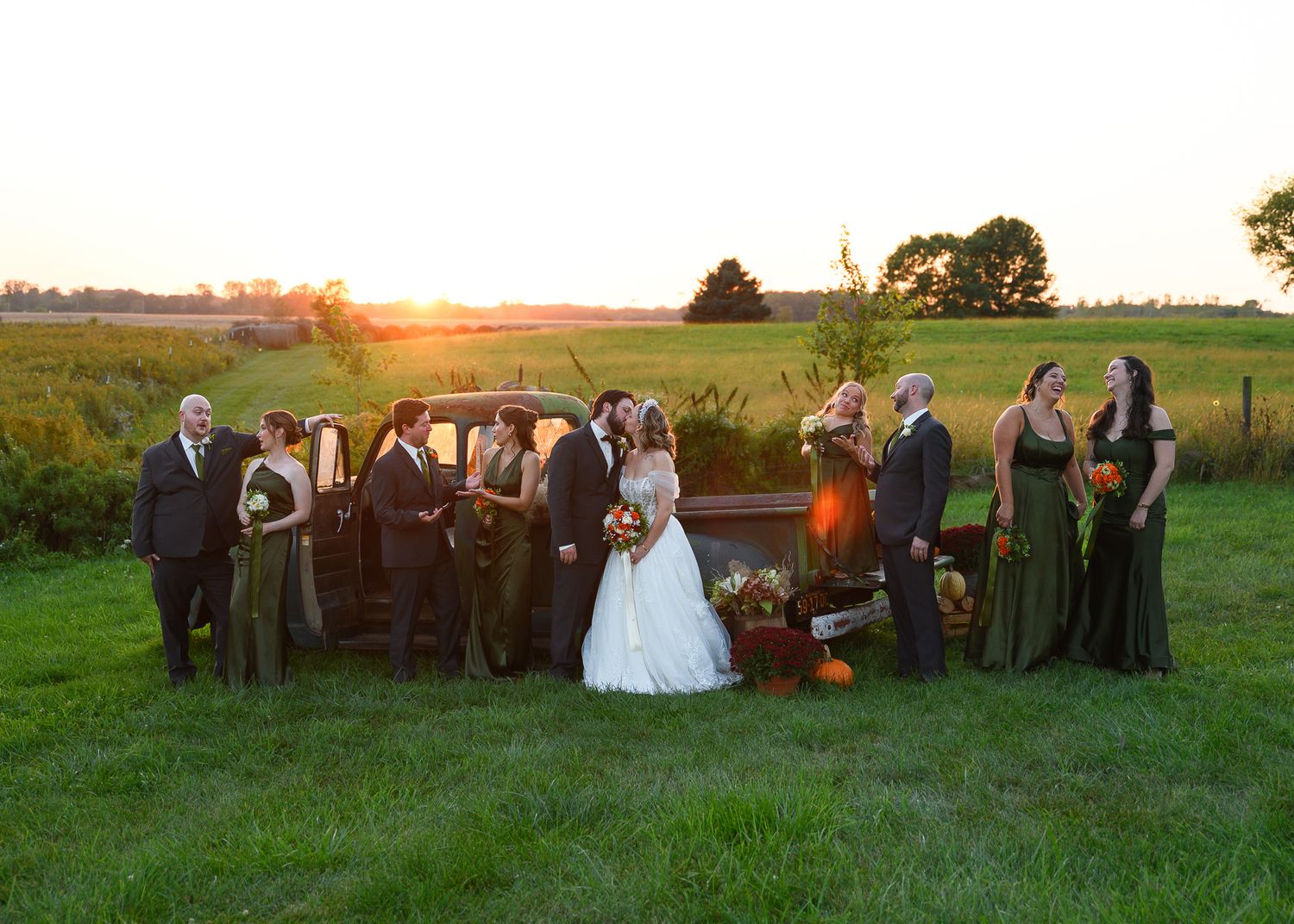 Wedding party lined up at sunset in rustic outdoor setting.