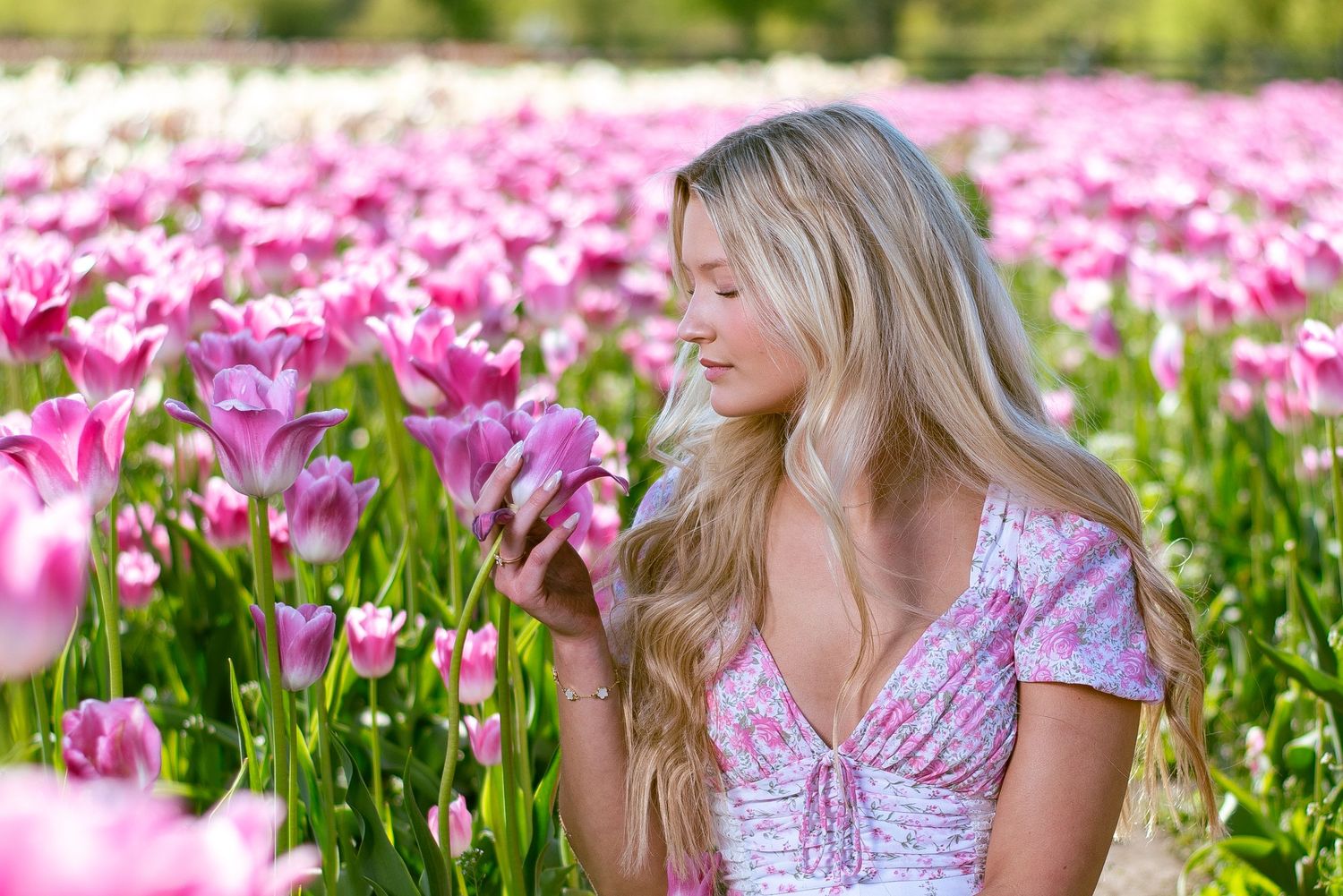 Portrait in a vibrant pink tulip field wearing a spring floral dress.