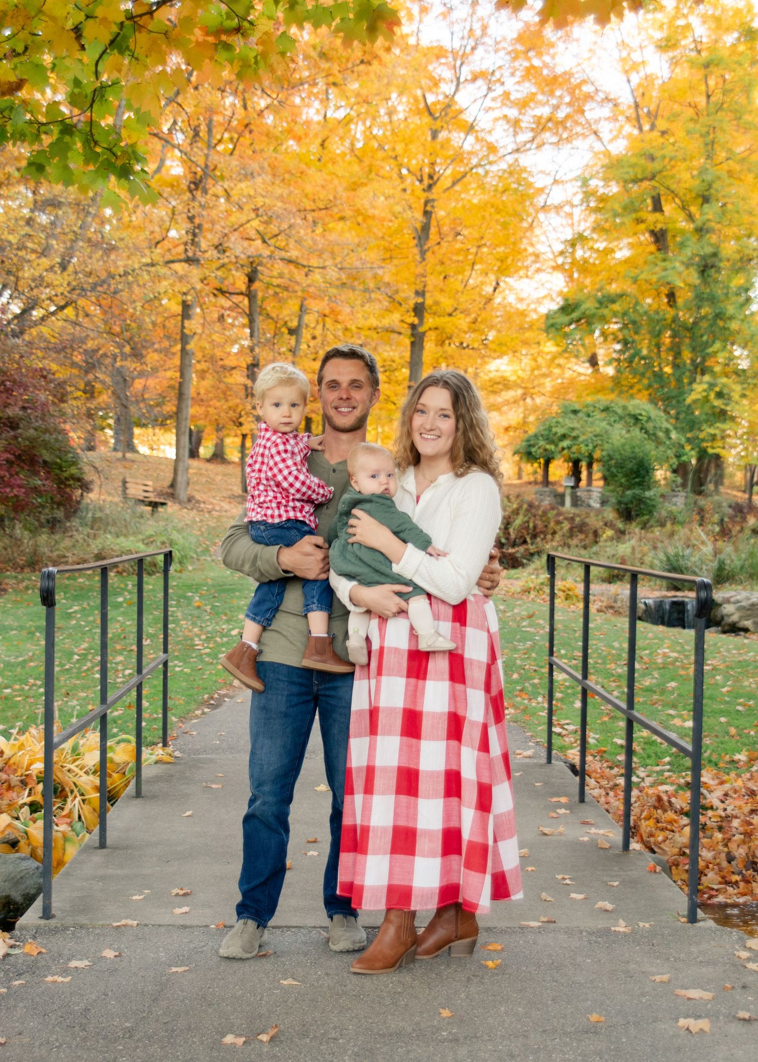 Family walking along an autumn path lined with vibrant yellow trees and fallen leaves.