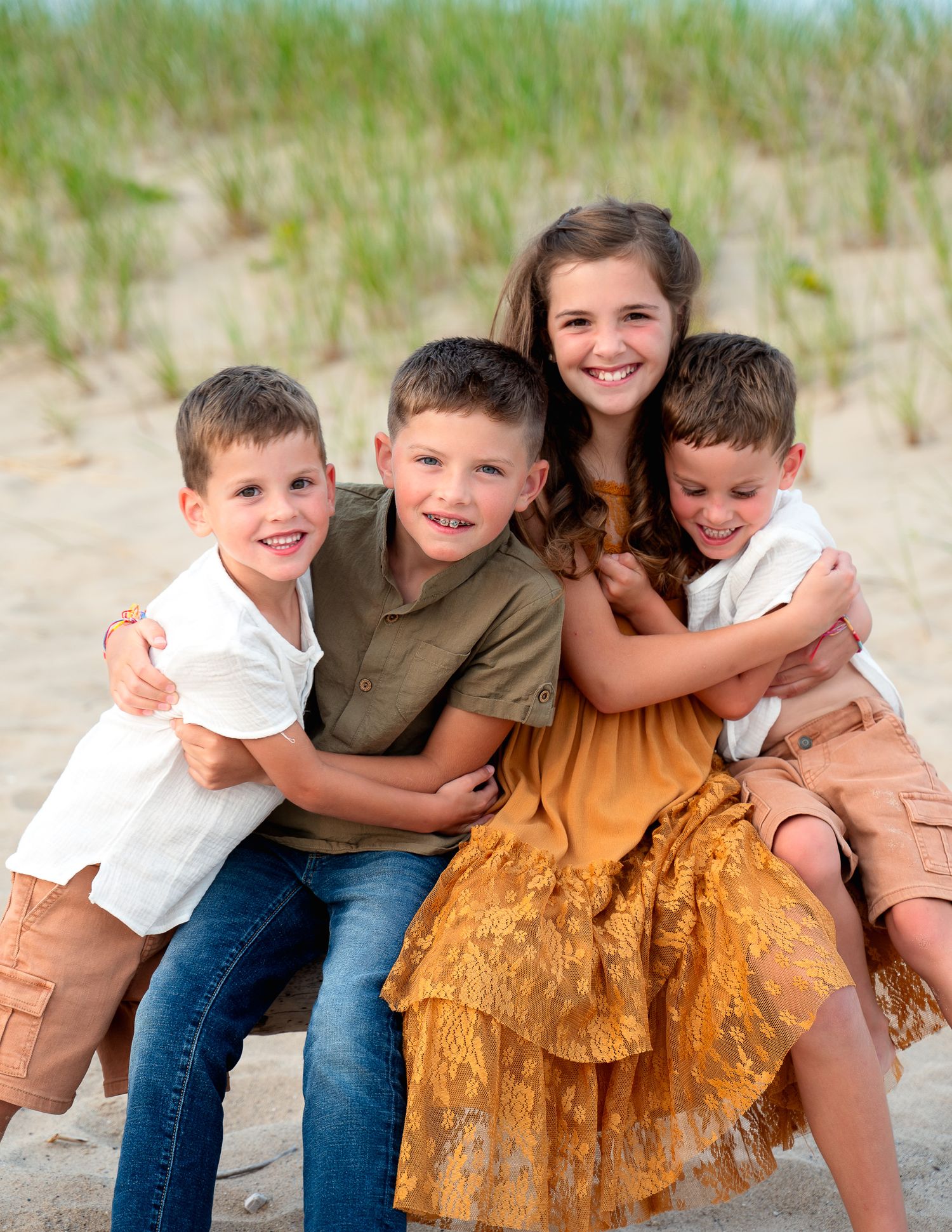 Group sitting close together on sandy beach wearing coordinated outfits.