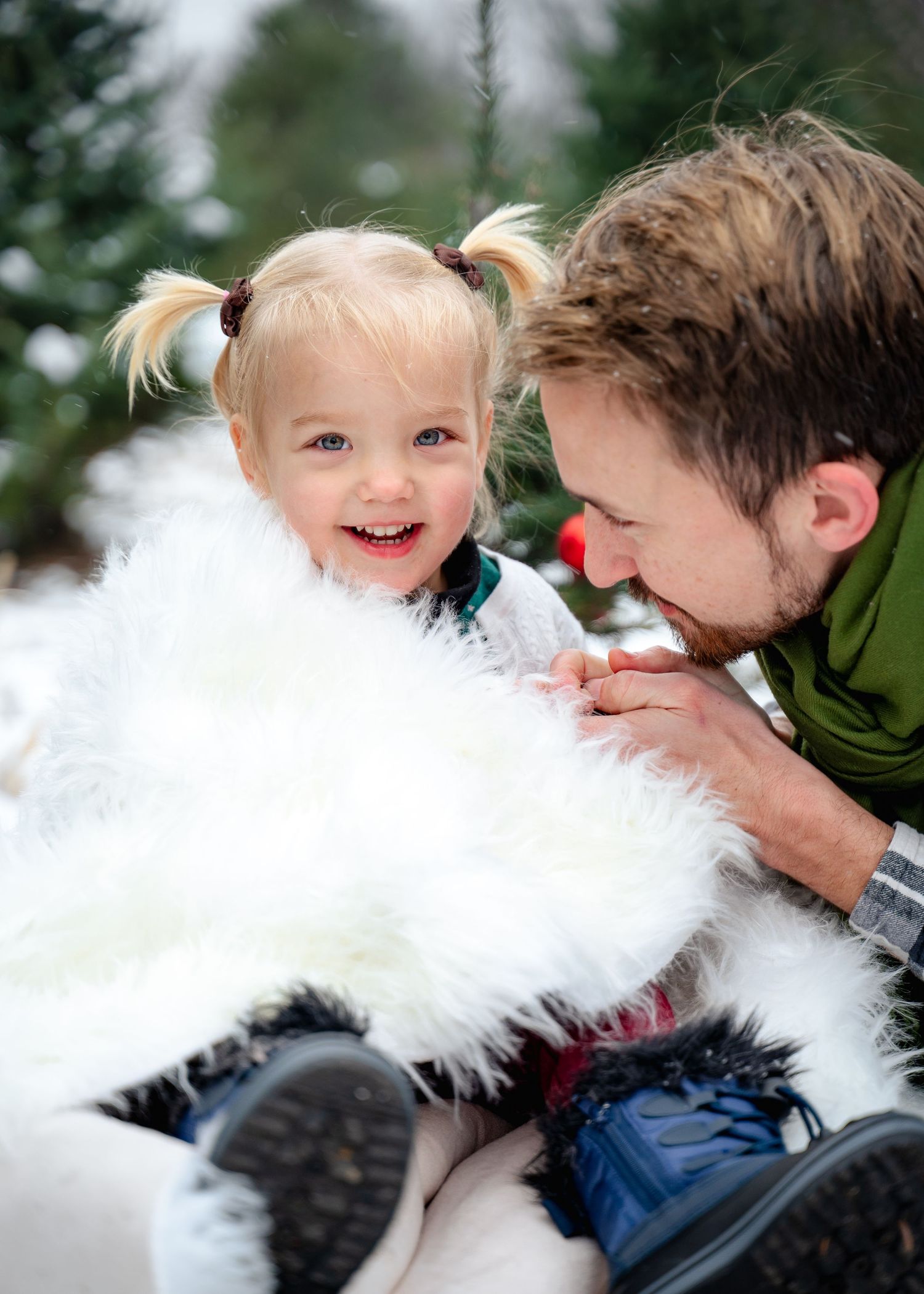 Playful winter moment with white furry blanket and evergreen trees.