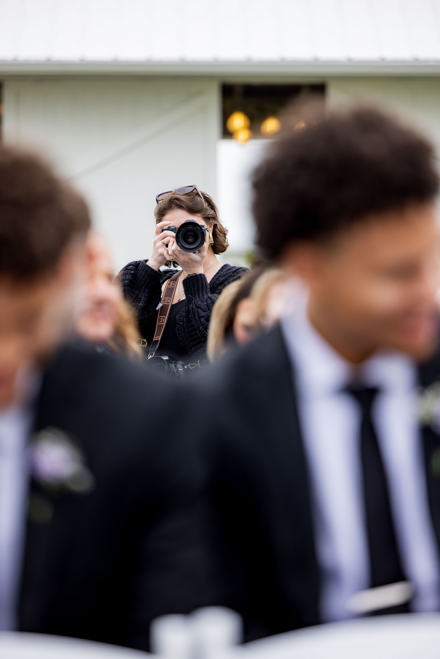 Photographer capturing photos at a formal event, surrounded by guests in dark suits and ties.