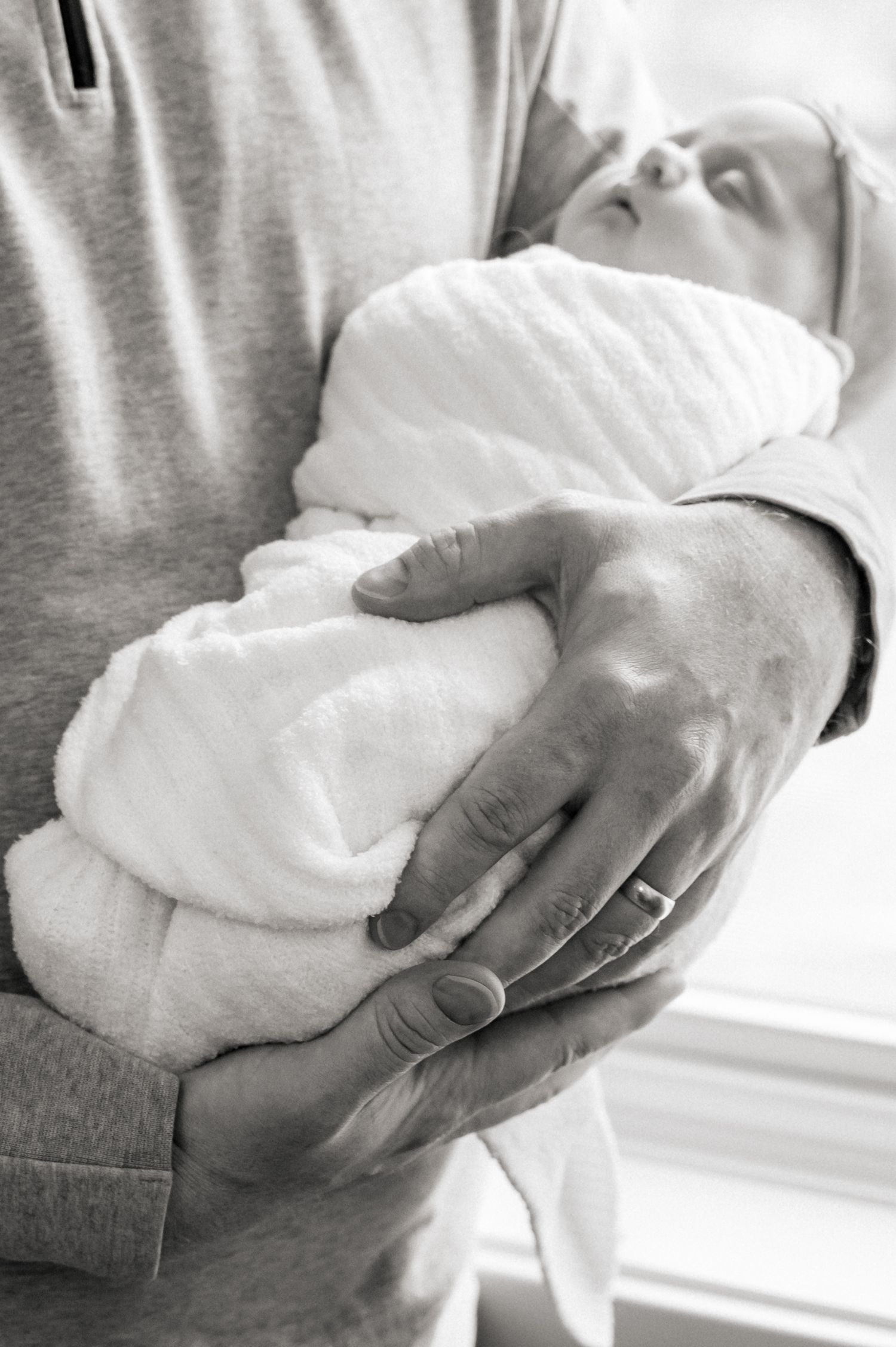 Black and white photos of a baby being cradled near a bright window.