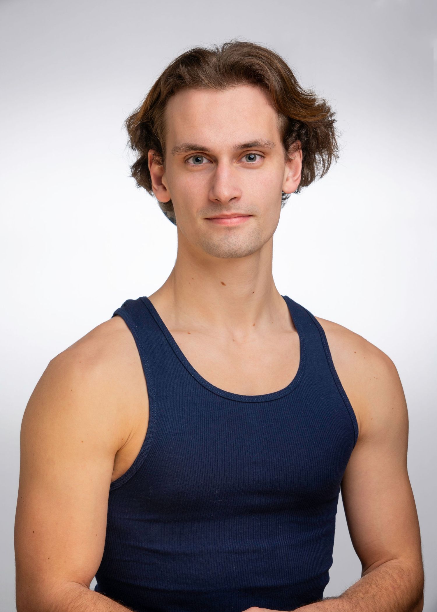 Athletic poses in a navy blue tank top against white studio background.