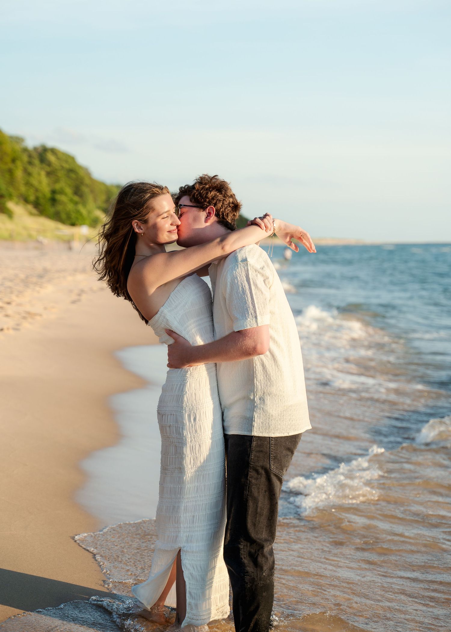Romantic couple in white clothing sharing intimate moment on sandy beach.