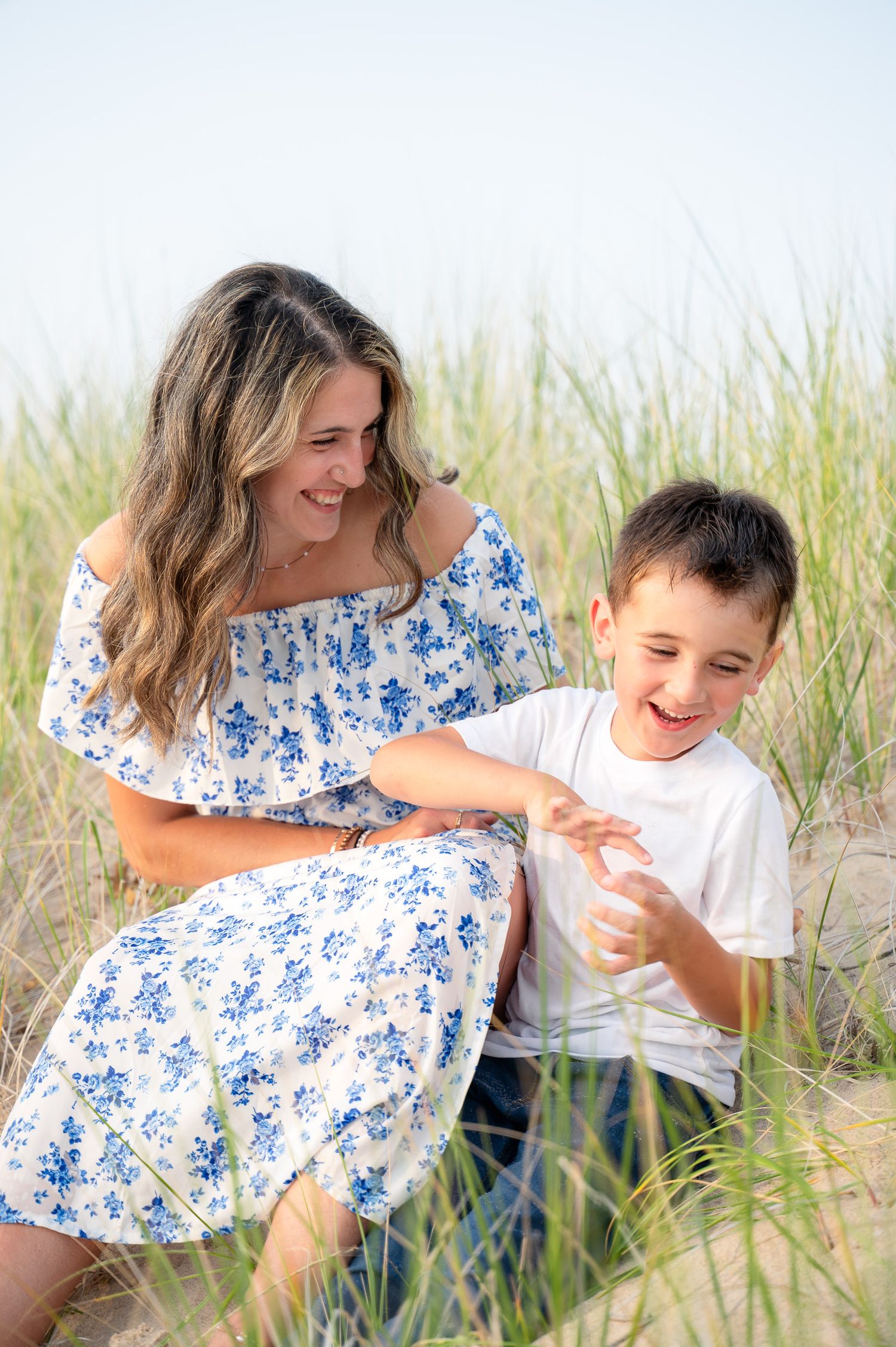 Summer portrait in tall beach grass with blue floral dress and white shirt.