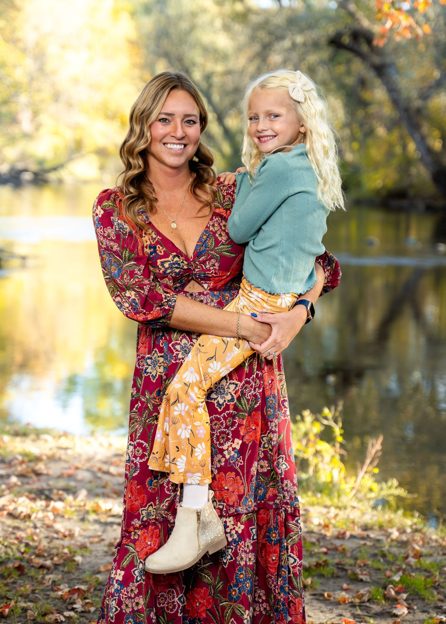 Joyful outdoor family portraits by water with autumn colors and floral dress.