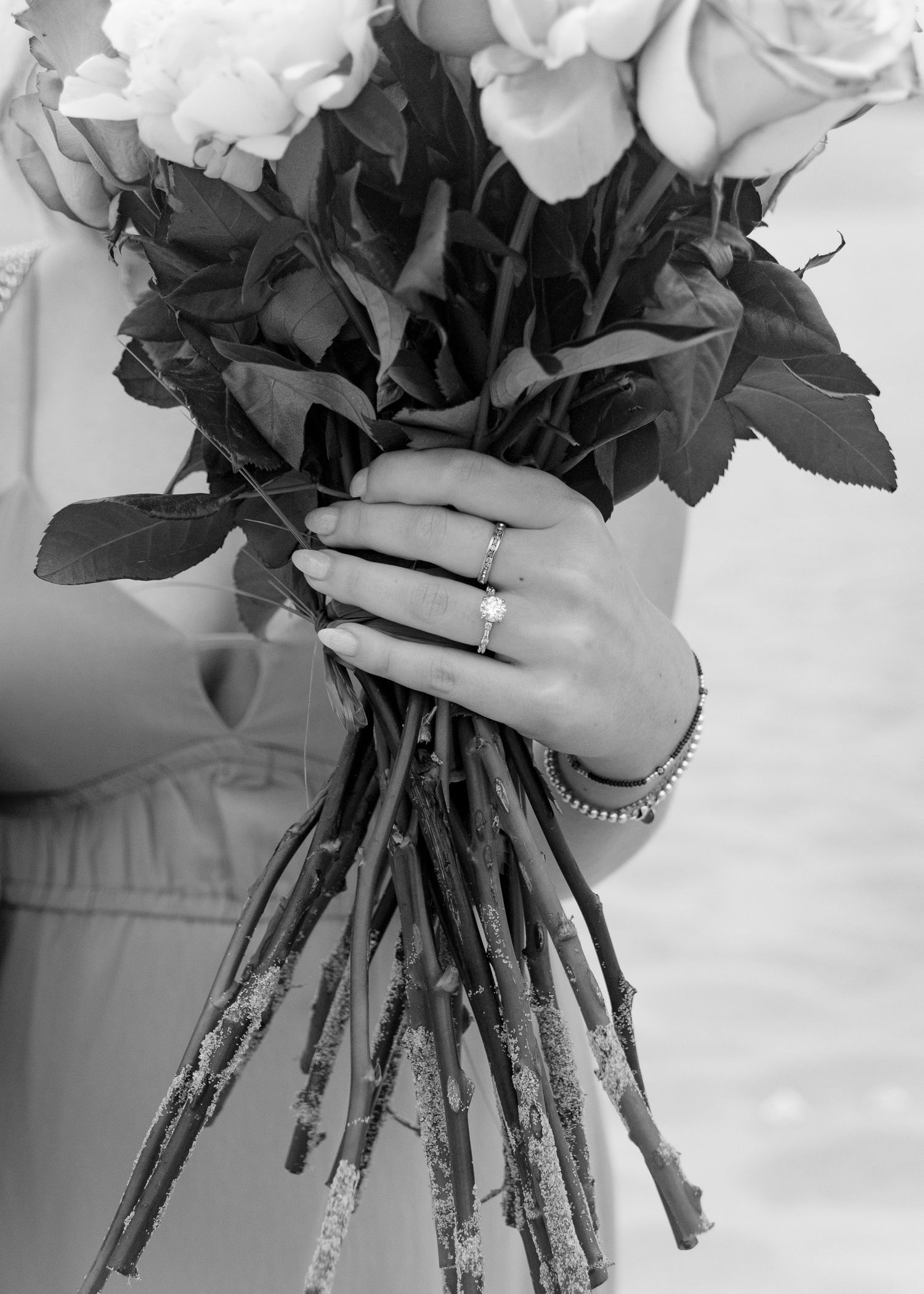 Close-up of white rose bouquet stems wrapped in decorative ribbon.