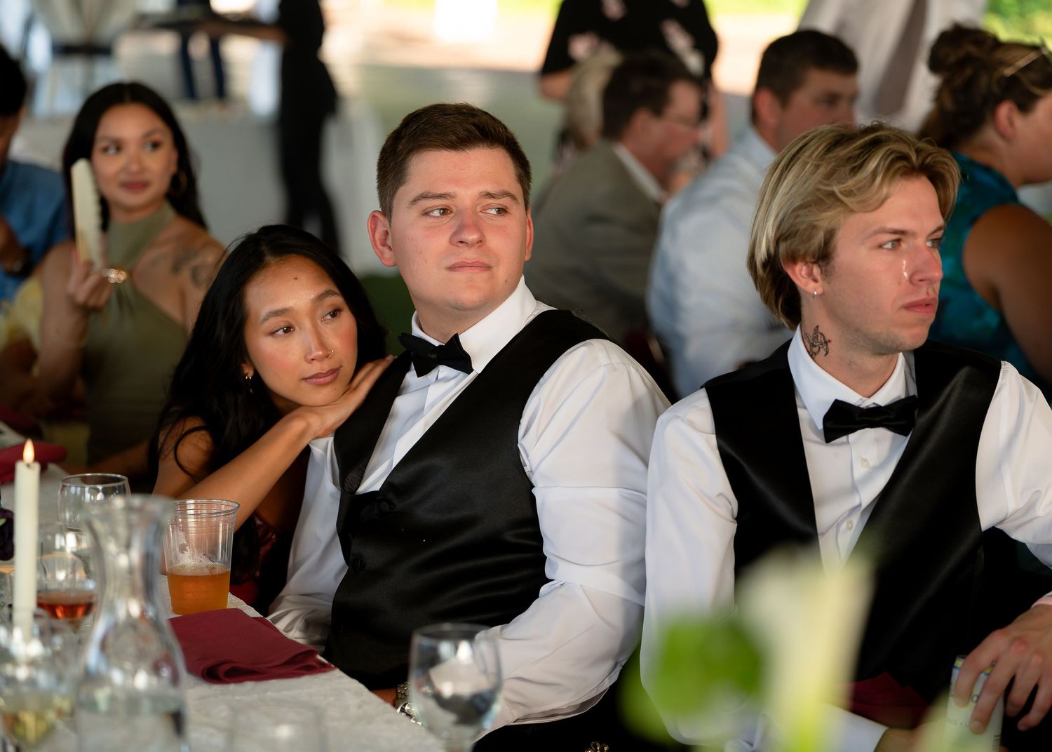 Young adults in formal attire seated at a banquet table during an elegant event or wedding reception.