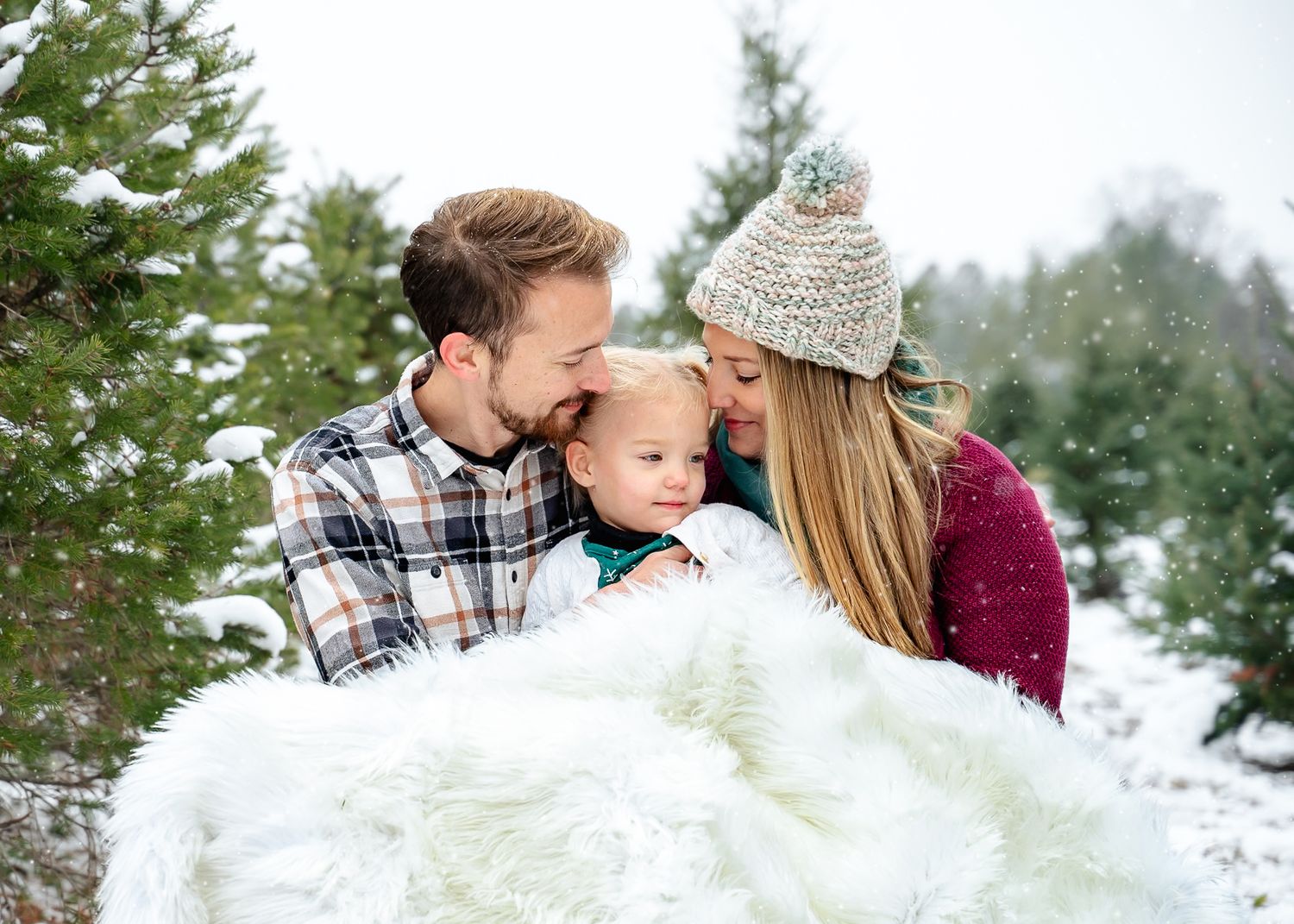 Intimate winter moment wrapped in white furry blanket among snowy evergreens.