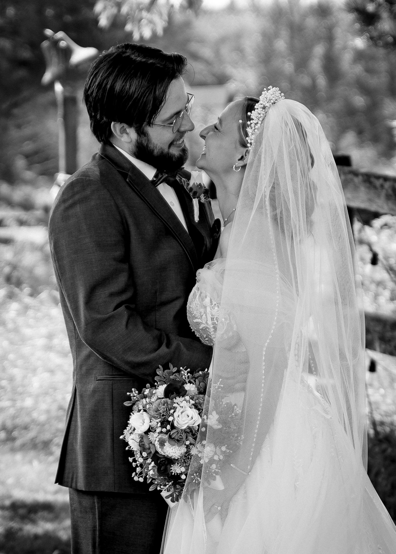 Black and white romantic wedding portrait captured in an outdoor garden setting.