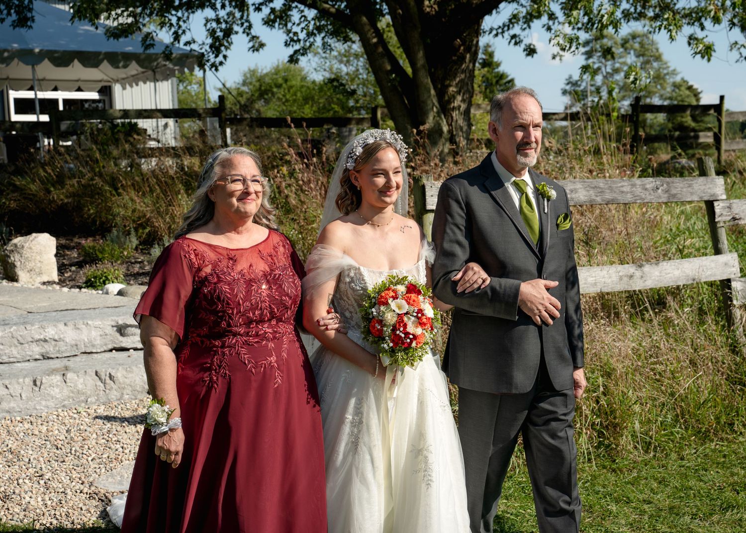Wedding party members pose together on a stone path during an outdoor celebration.