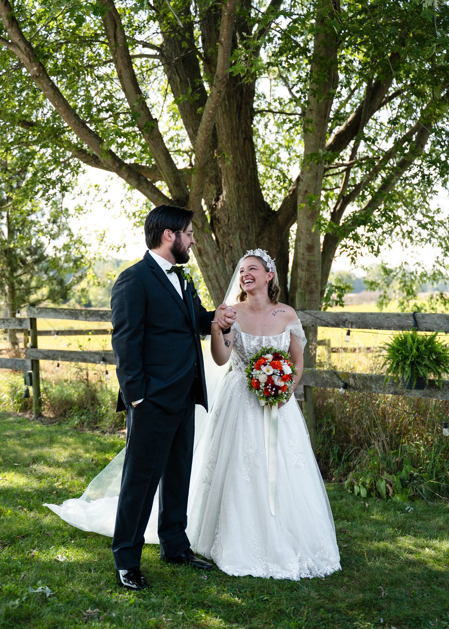 Romantic outdoor wedding photos under tree canopy with white dress and formal attire.