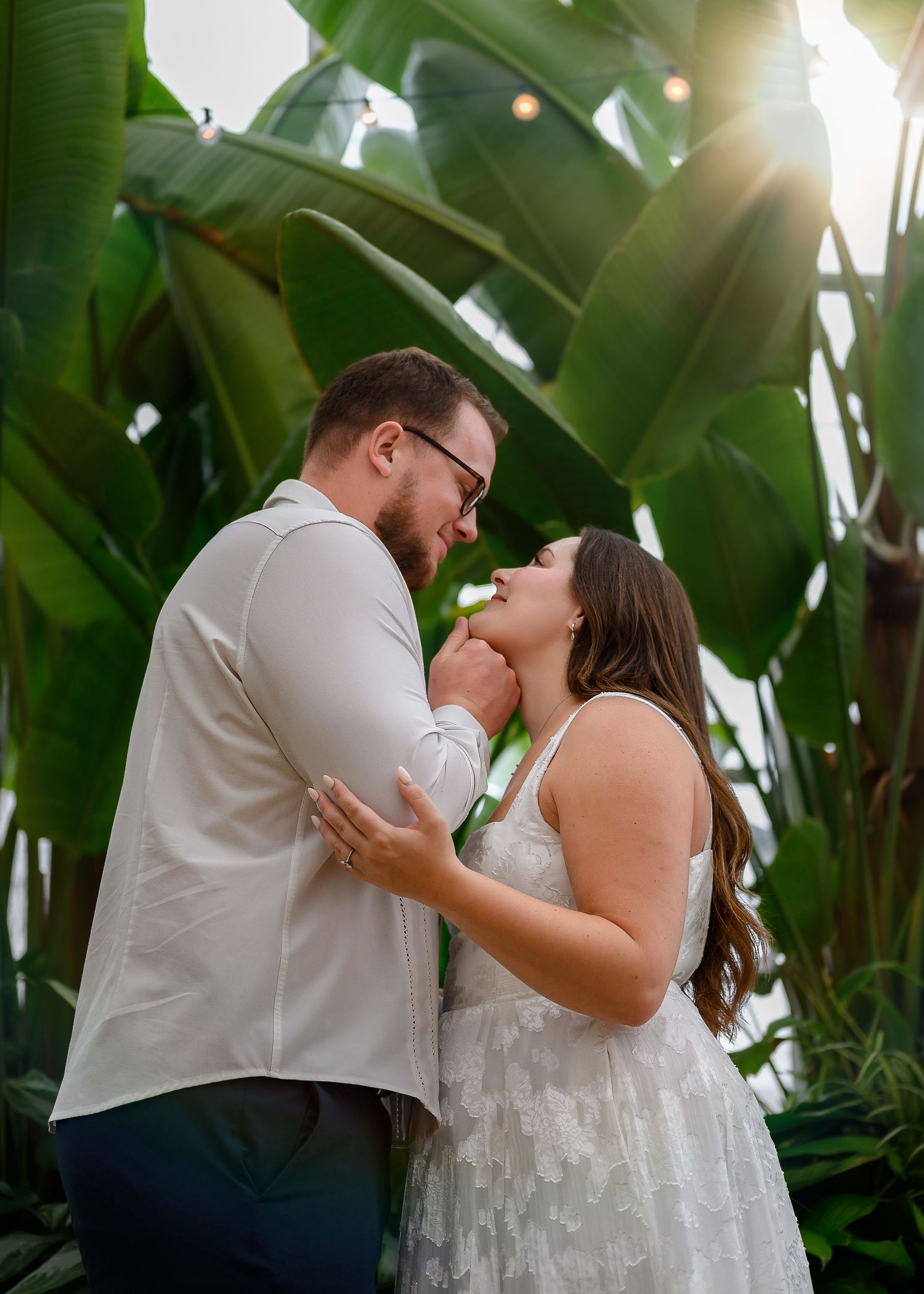 A romantic couple shares intimate moments among lush tropical palm trees during a photo session.