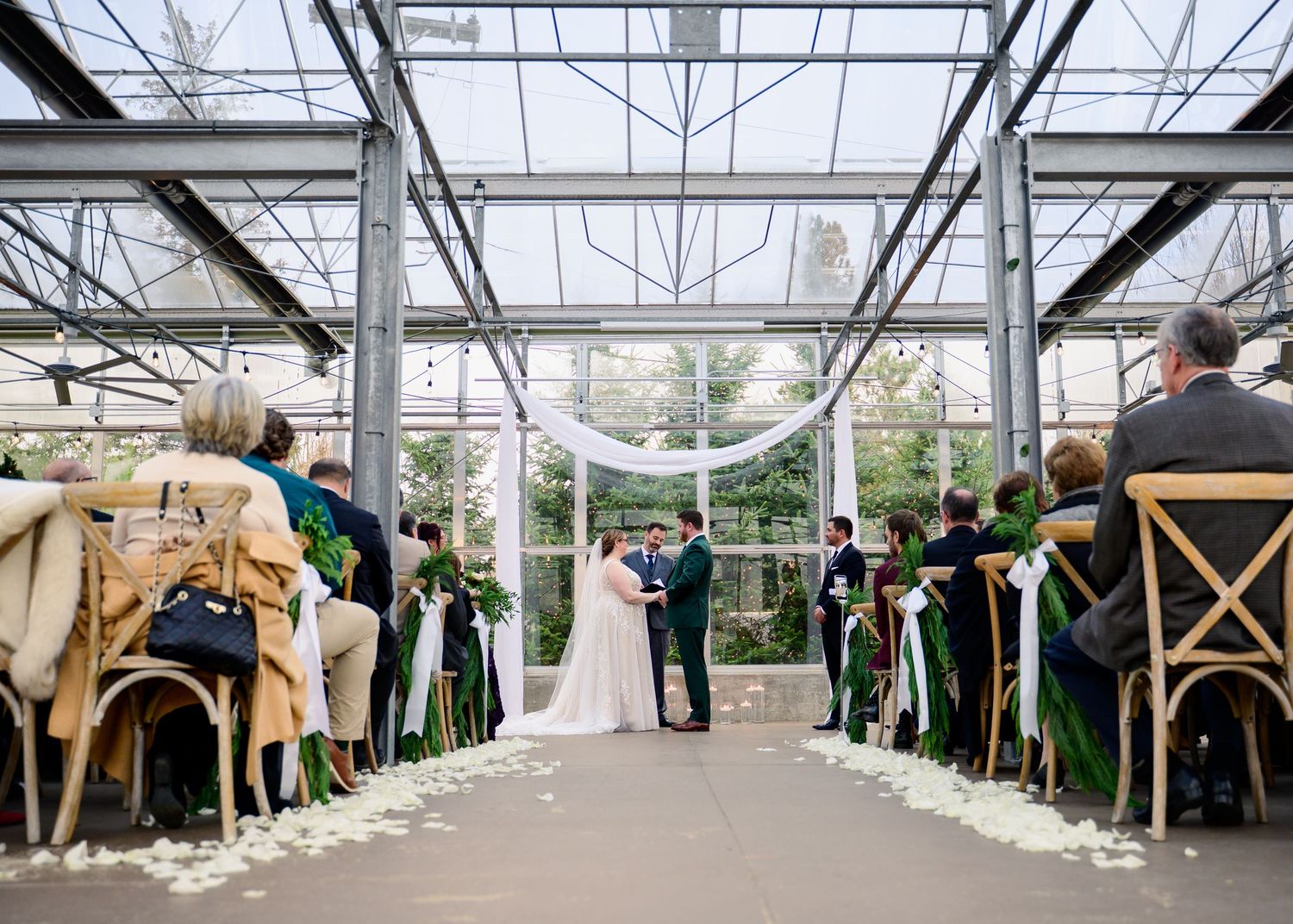 An elegant greenhouse wedding venue with rows of chairs set up for a ceremony.