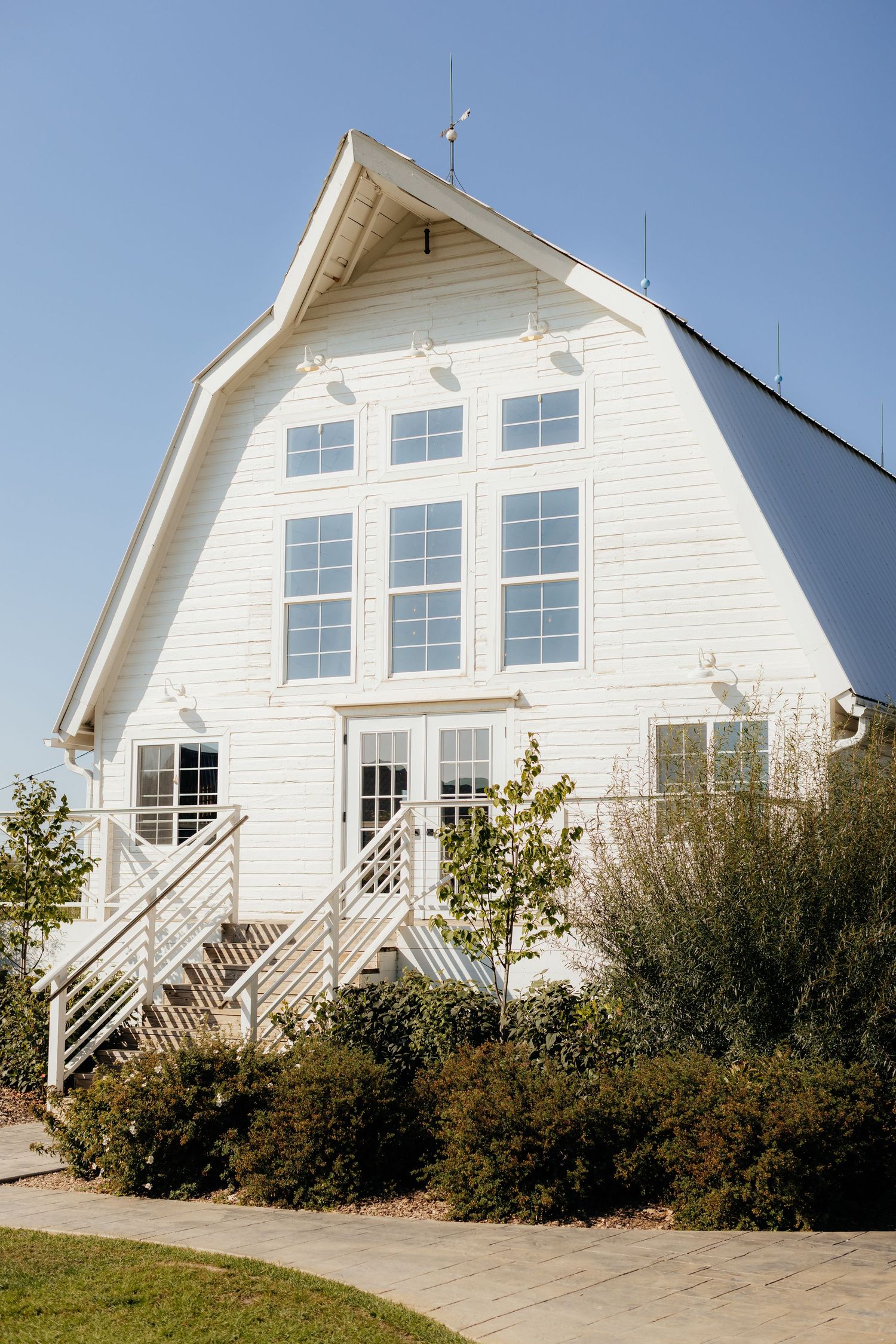 White barn-style buildings with multiple windows stand in a row against a blue sky.