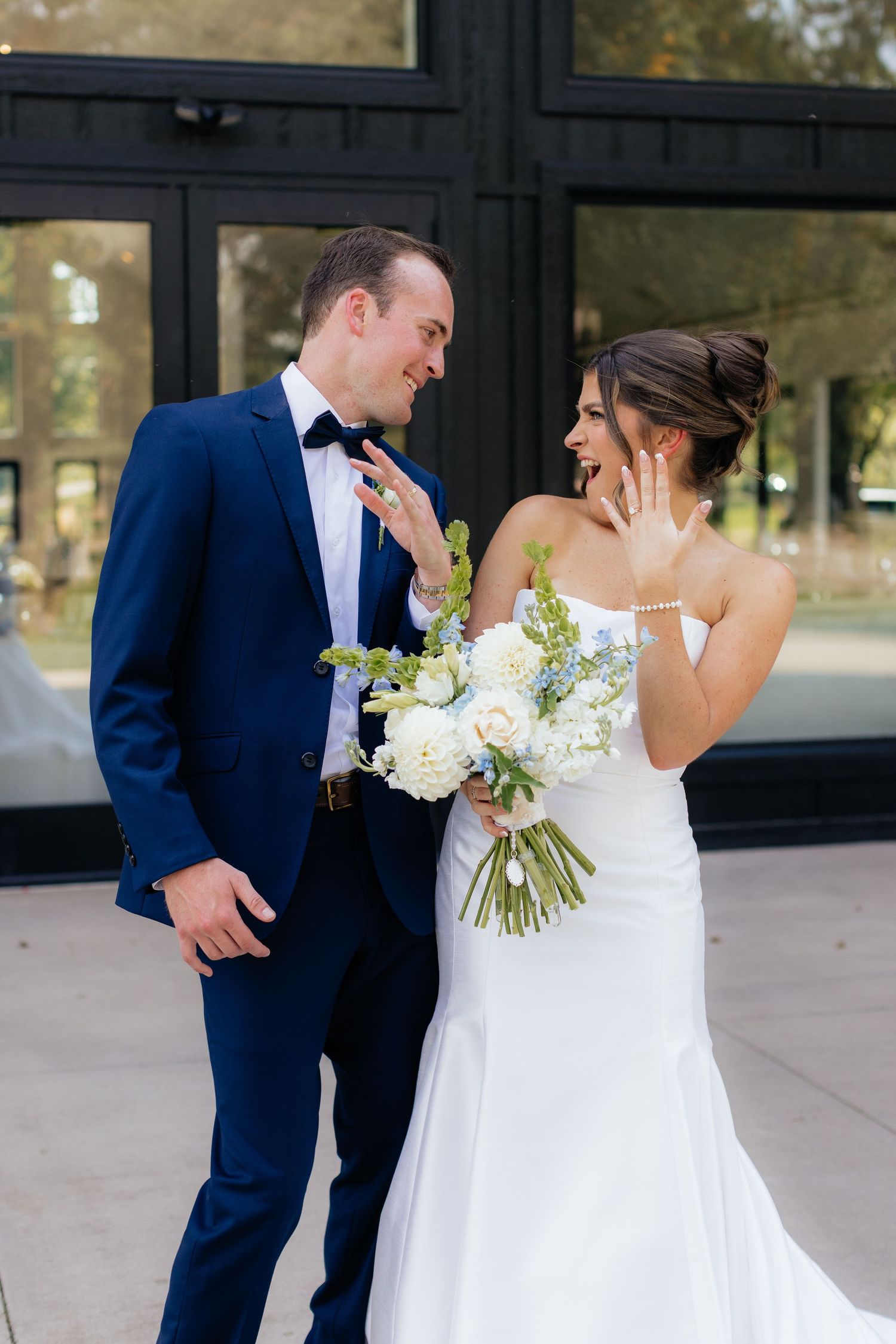 Wedding couple sharing a joyful moment outside a modern building.