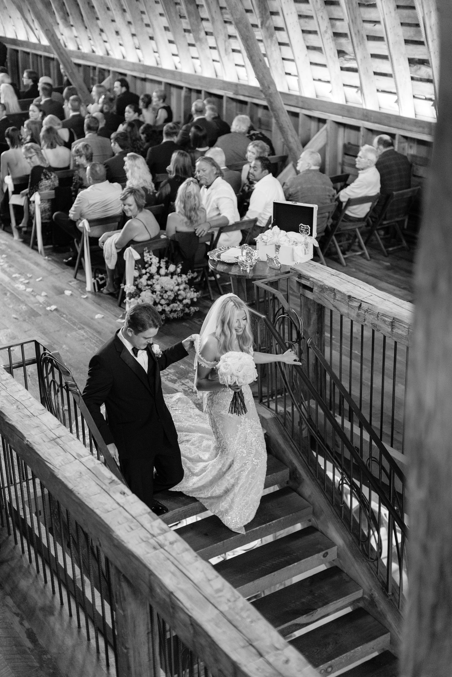 Wedding ceremony guests seated in wooden pews inside a historic venue with natural lighting.