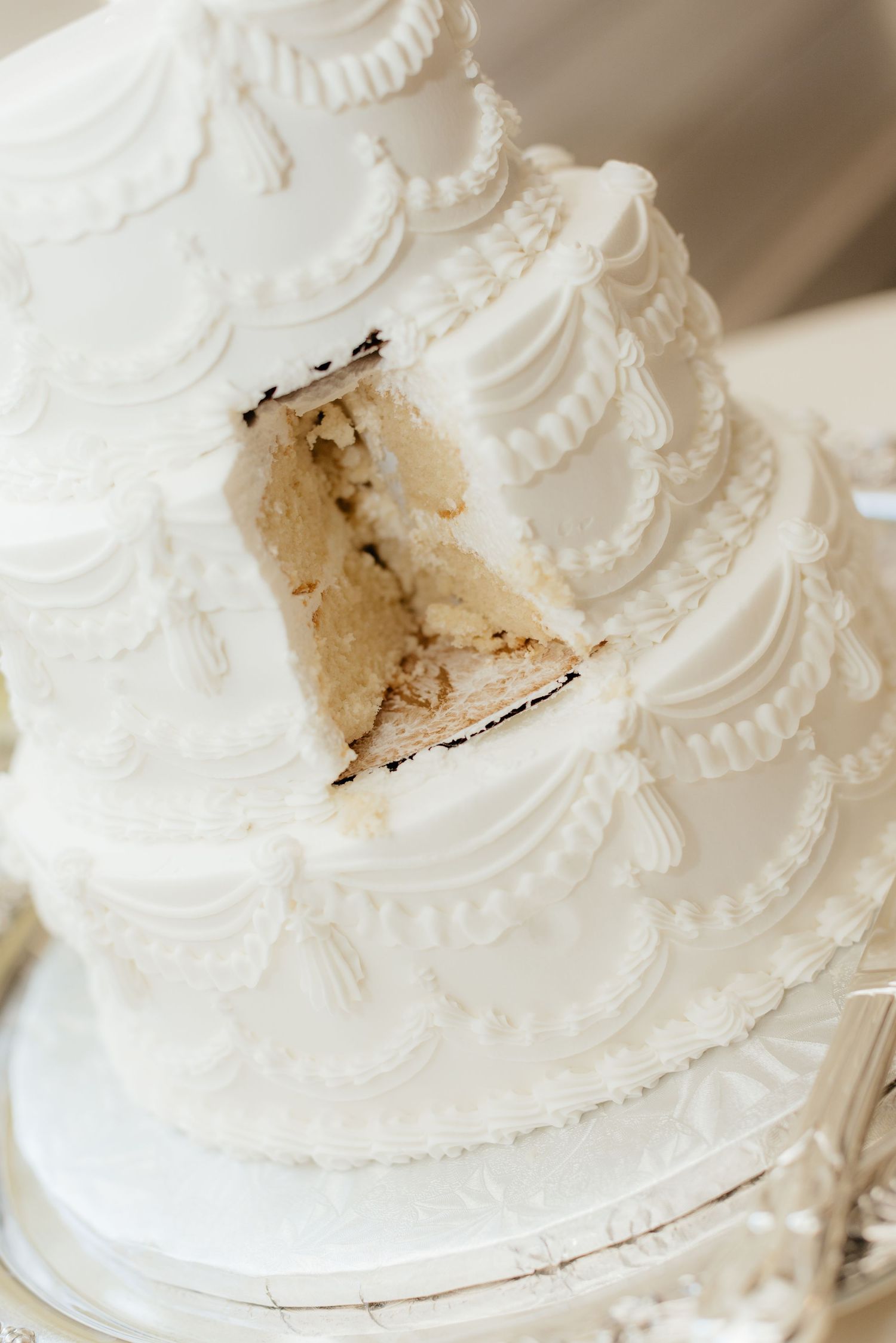 Close-up detail of a classic white wedding cake with delicate frosting patterns.