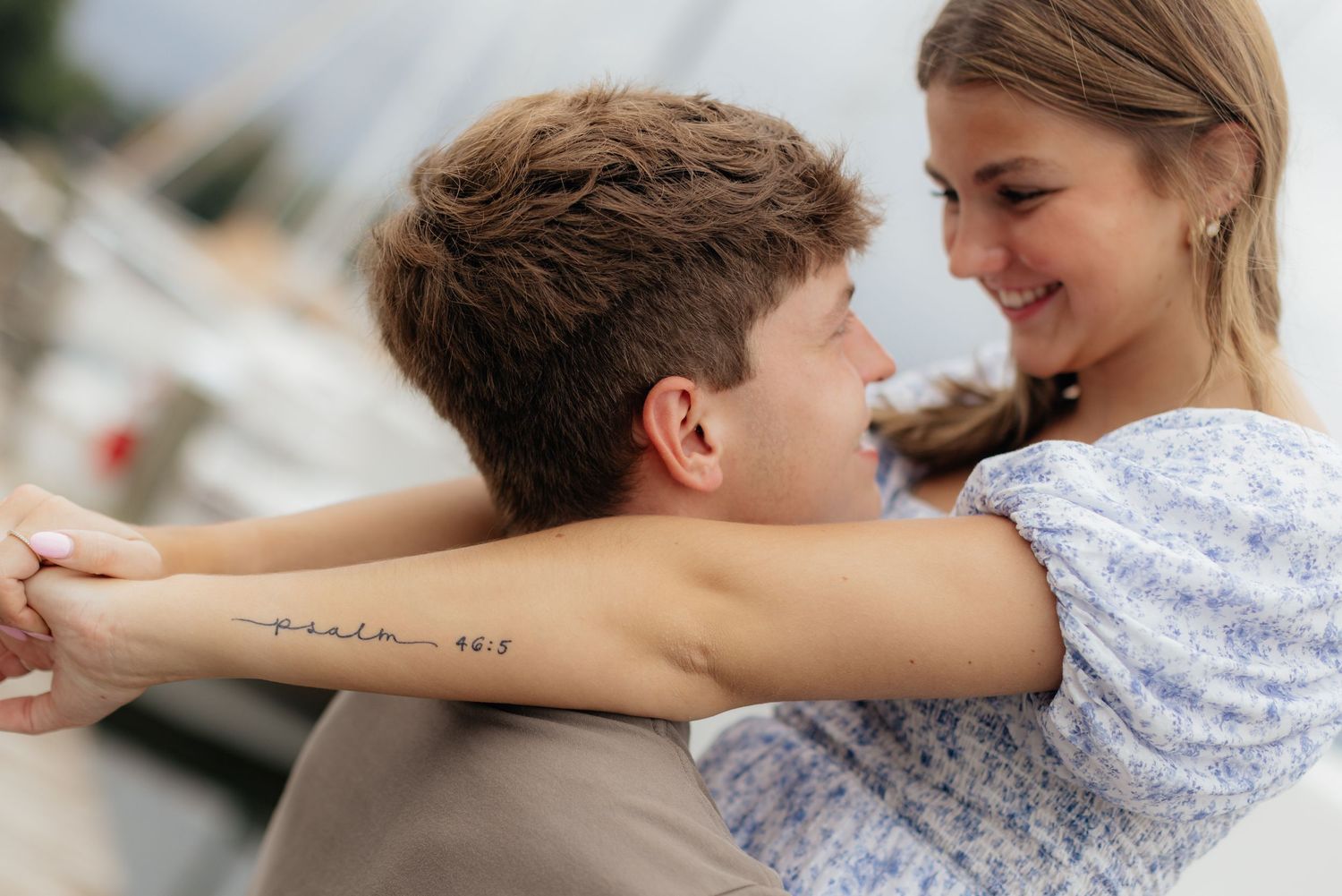A close-up romantic moment between a couple at a marina.