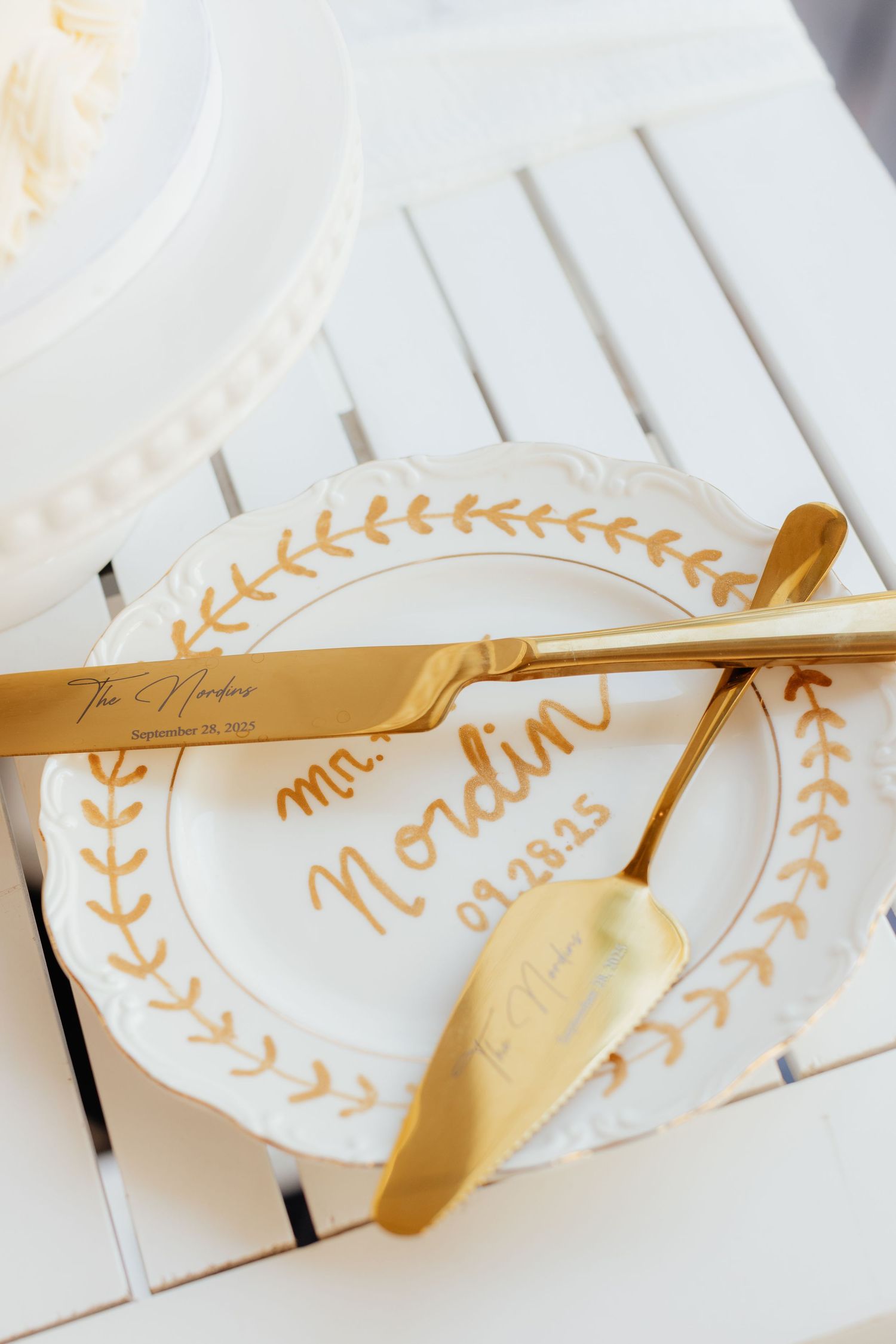 Gold serving utensils on white plates with delicate leaf pattern details.
