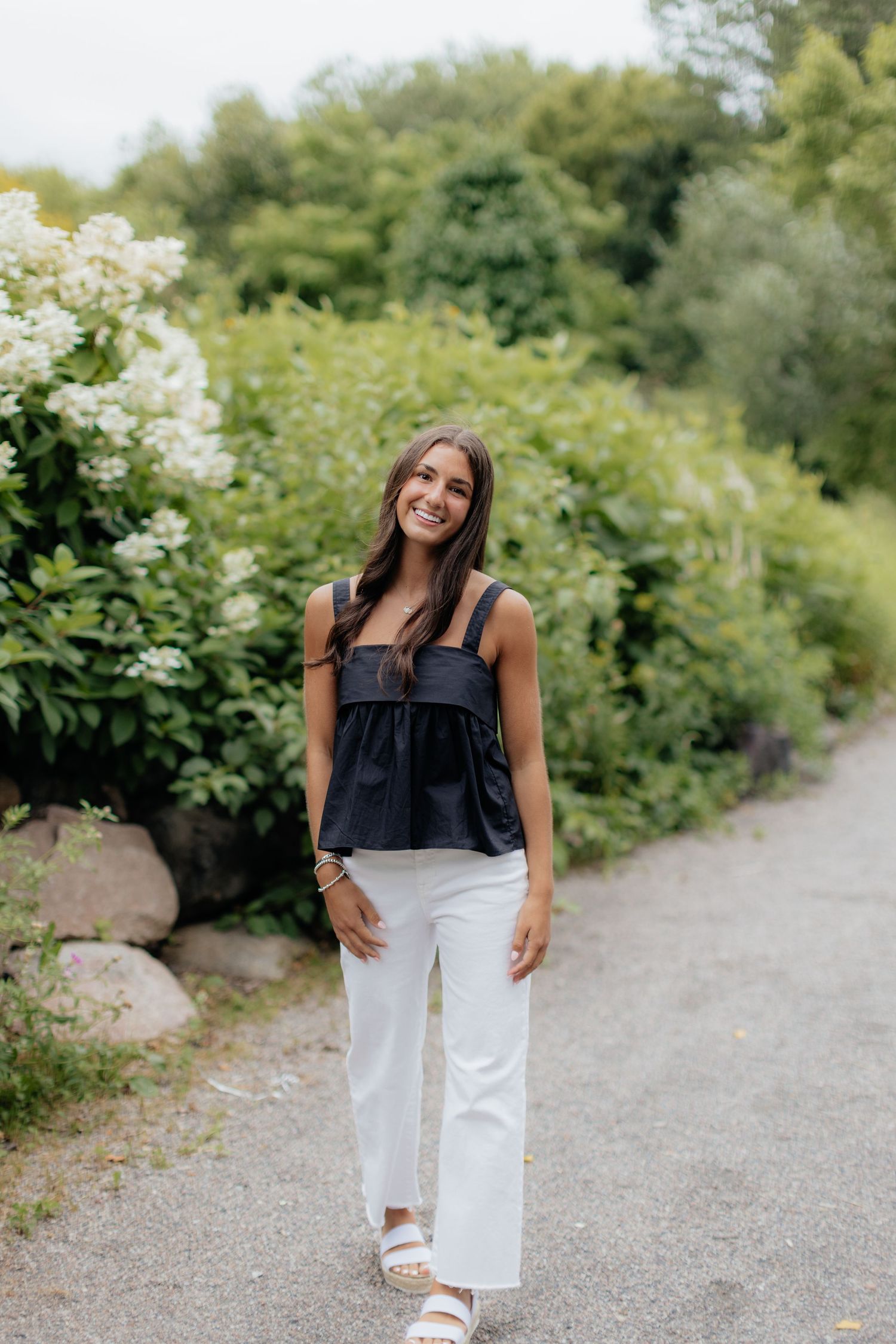 A black sleeveless top paired with white pants is styled for a casual summer look.