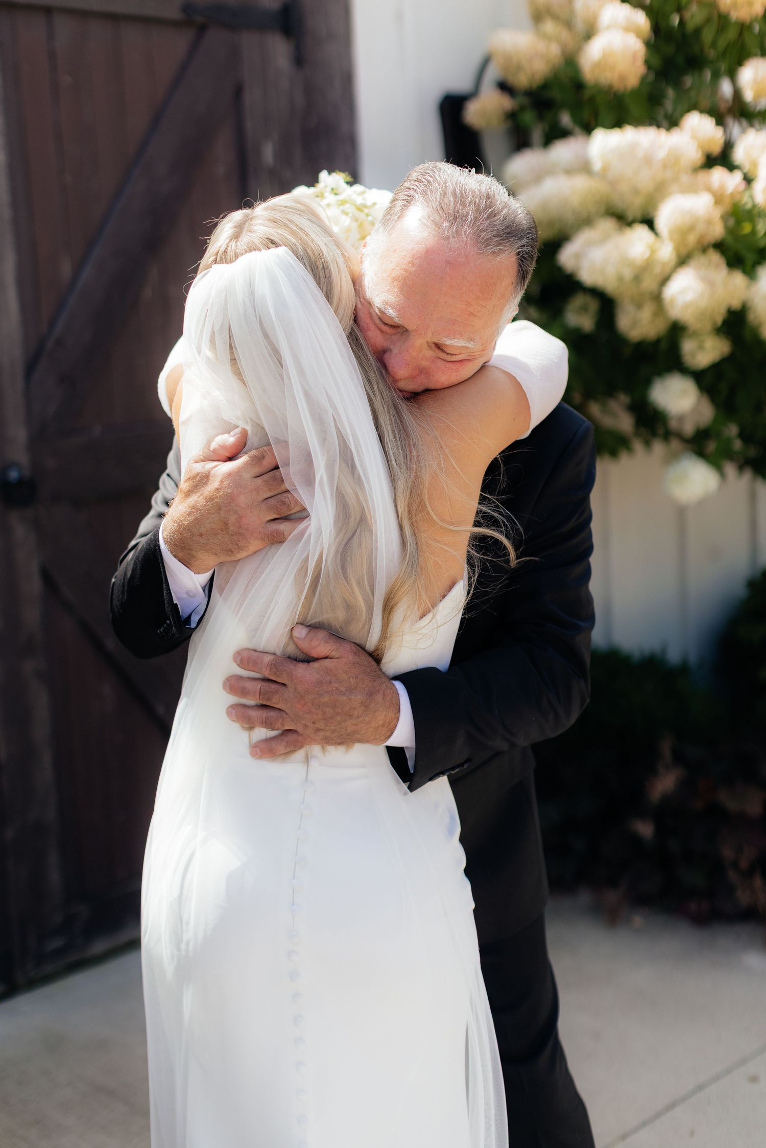 Tender embrace between bride and father during wedding ceremony.