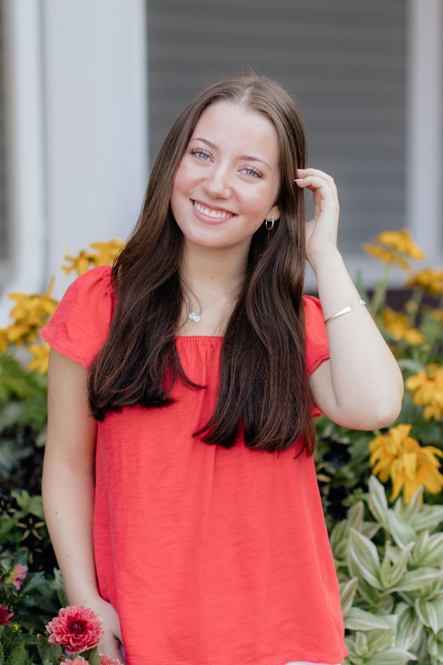 Portrait series in bright coral top against floral garden background.
