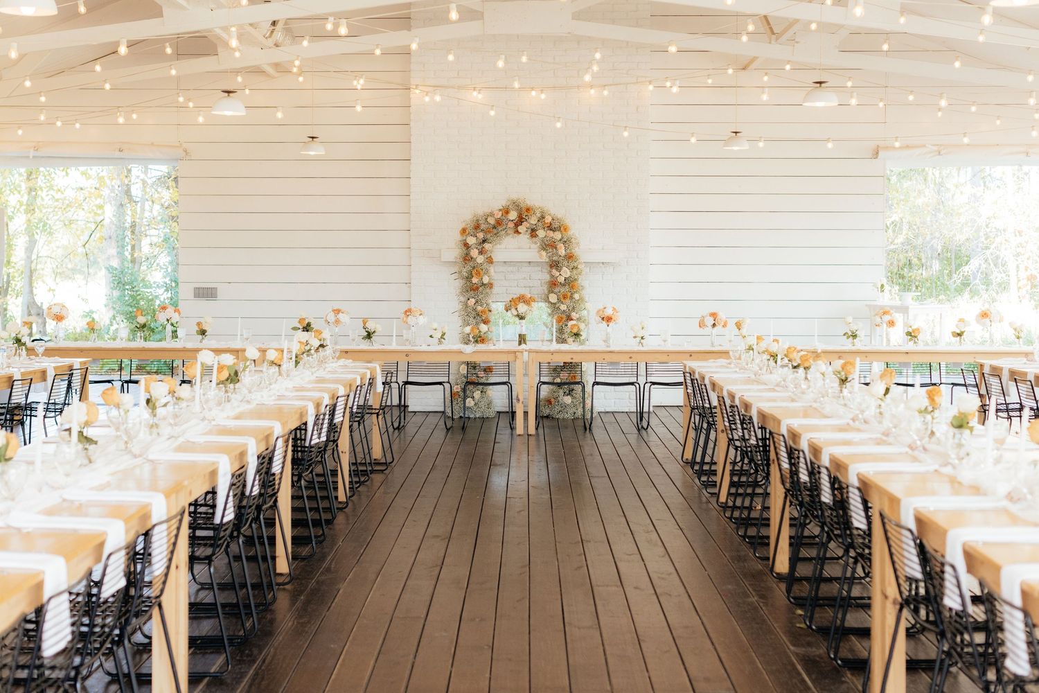 White rustic barn venue interior with wooden floors and string lights for a wedding reception.